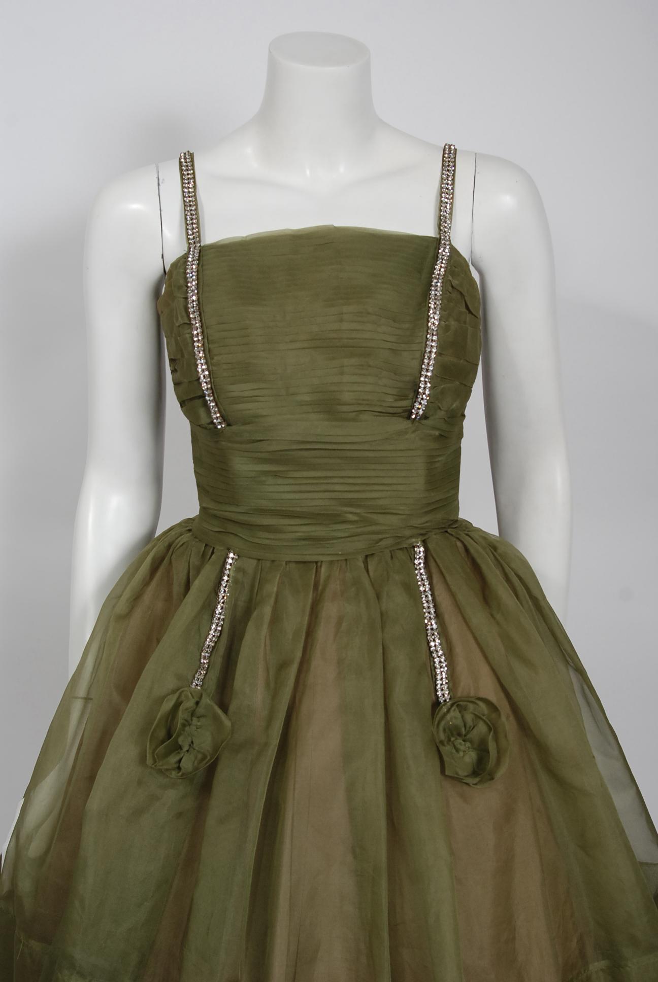 Fashioned from rich olive-green light weight silk-organza, this 1950's creation has everything a woman wants. The boned bodice has a gorgeous pleated texture shelf-bust design. I adore the sparkling rhinestone detail which is so playful and elegant