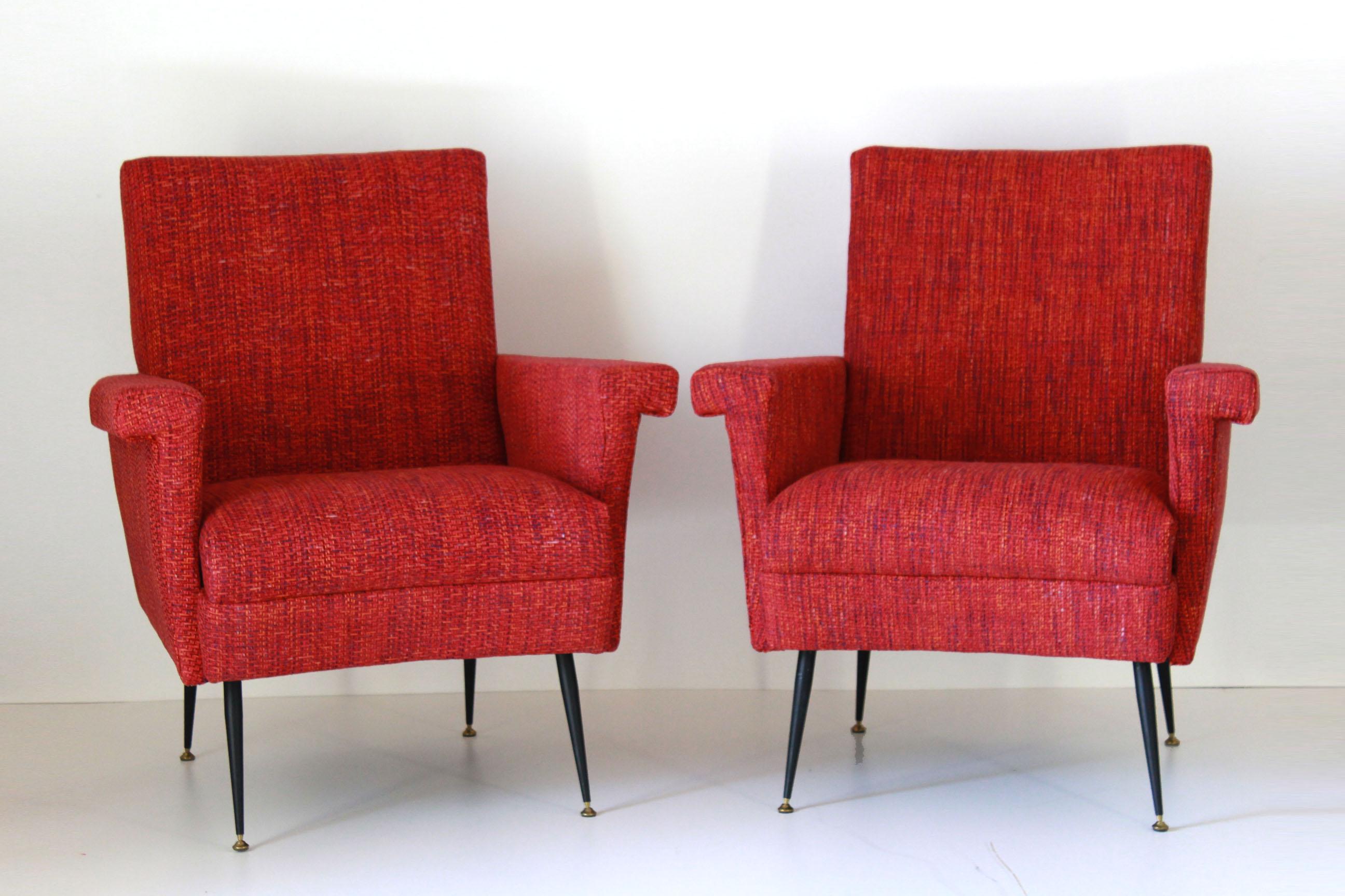 A pair of two vintage armchairs with red cover and iron and brass feet. Typical italian mid century style.

The vintage armchairs have been fully restored. The filling of the seat has been changed and the cover textile changed with a brand new