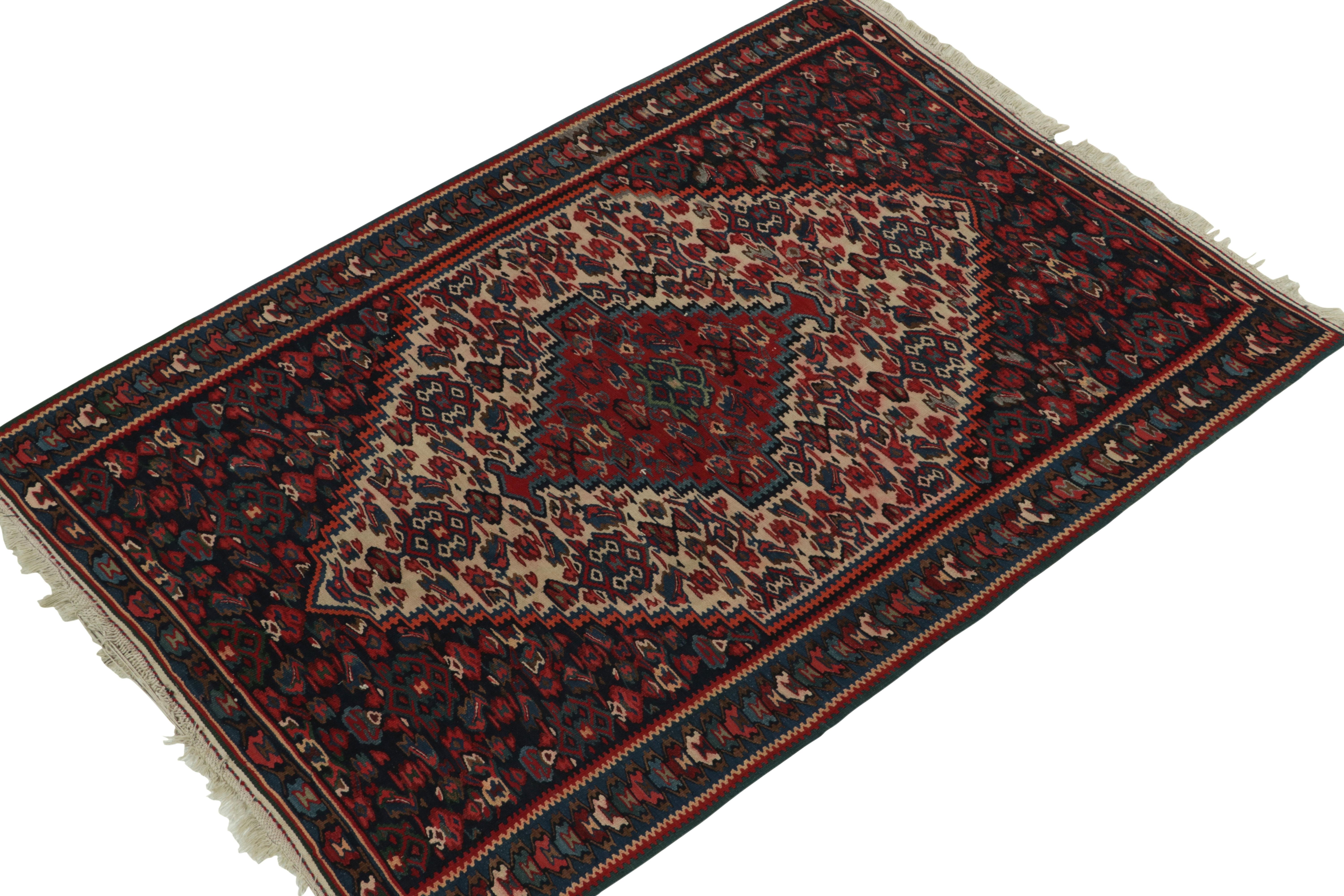 Hailing from Persia circa 1950s, a mid-century kilim rug now joining Rug & Kilim’s vintage selections. The Senneh kilim design connotes a union of  medallion and all-over field patterns with a rich array of burgundy red, aegean blue and accenting