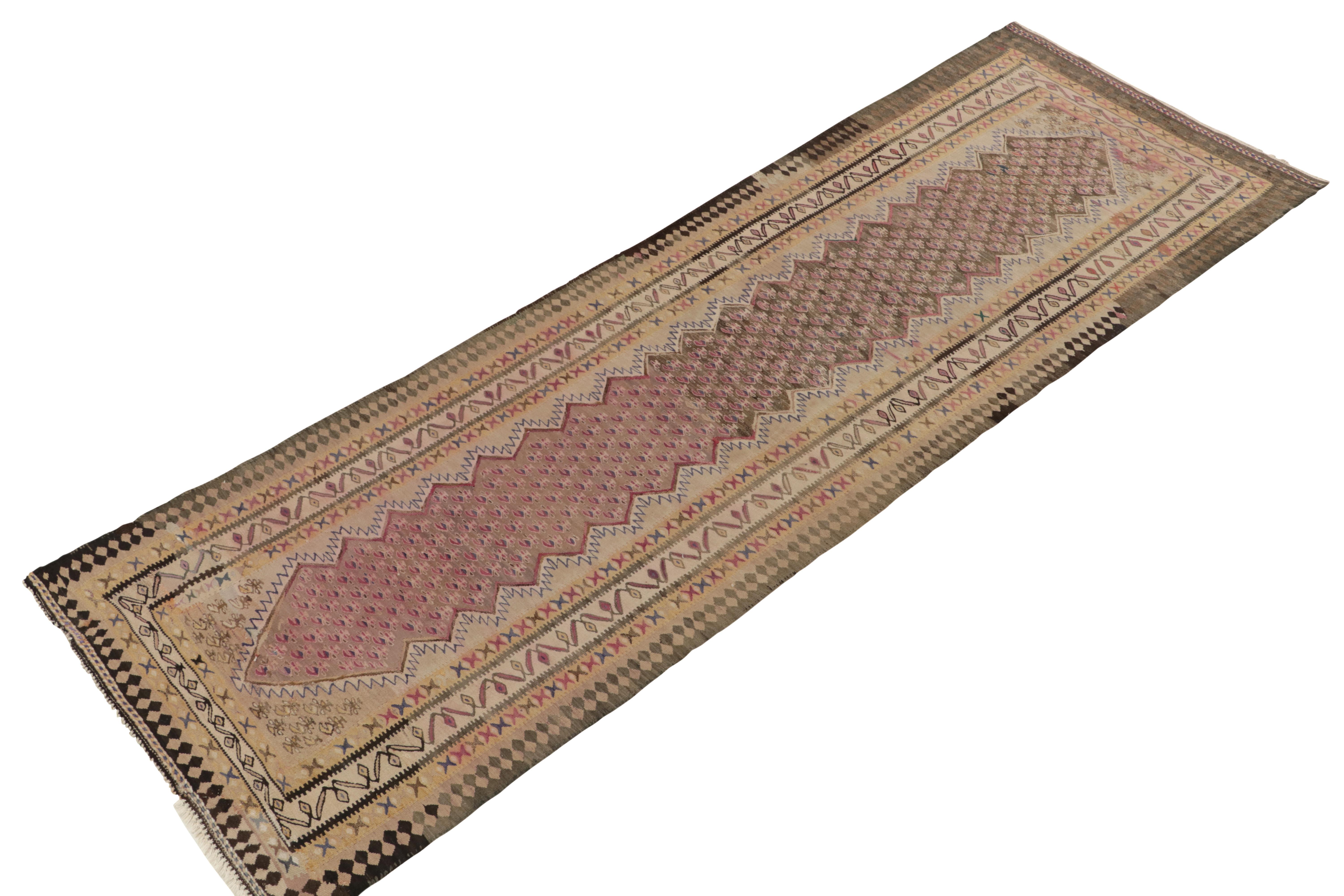Handwoven in wool circa 1950-1960, a 4x10 vintage Senneh kilim runner newly unveiled from Rug & Kilim’s most distinguished tribal curations. 

This particular Persian rug enjoys an elaborate pattern in unusual pink and pale indigo blue geometry