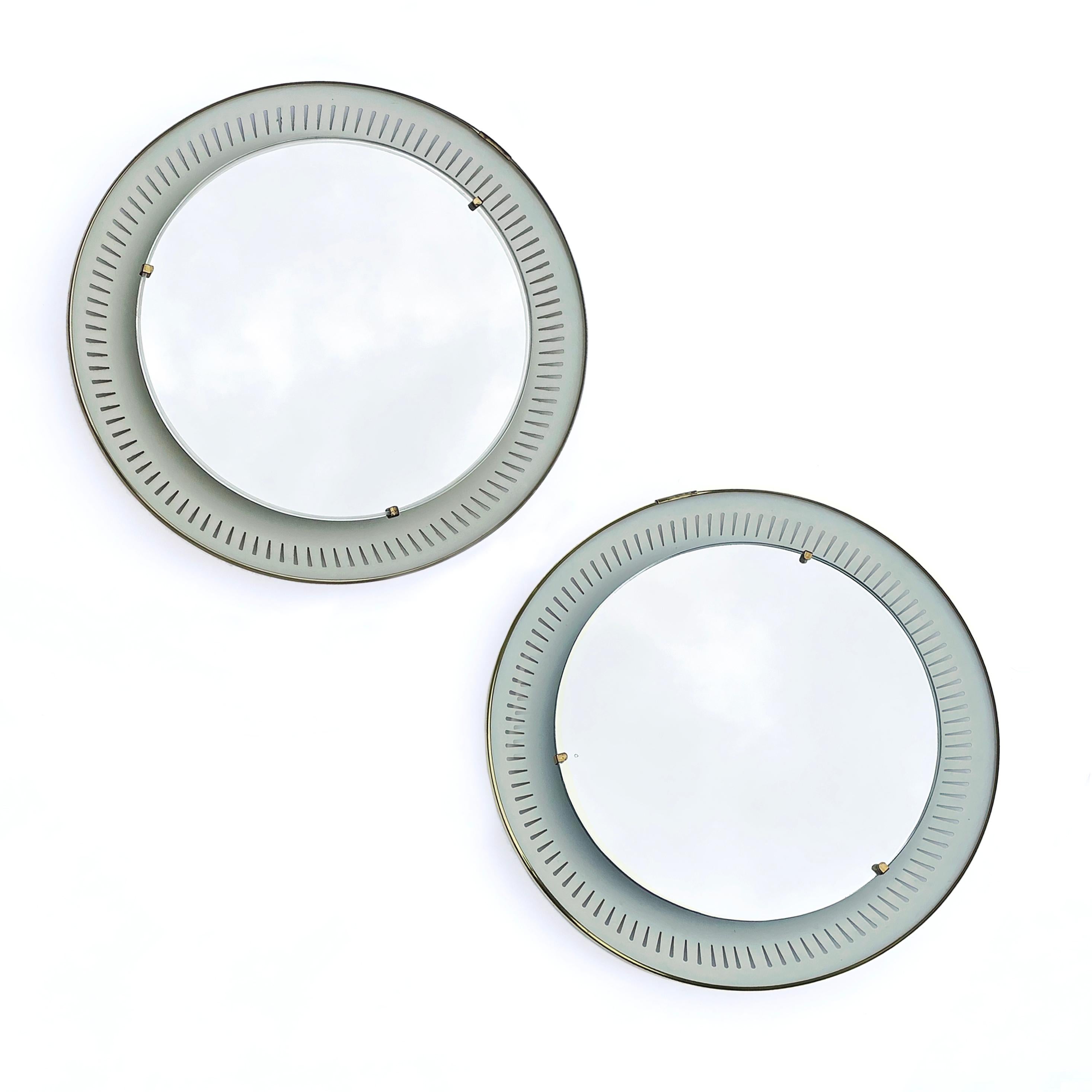Two beautiful, high-quality illuminated wall mirrors by the German Company Hillebrand from the 1950s. 
The round crystal mirror sits on a metal reflector with slit decoration. In addition, the reflector is decorated with a brass rim. The glass