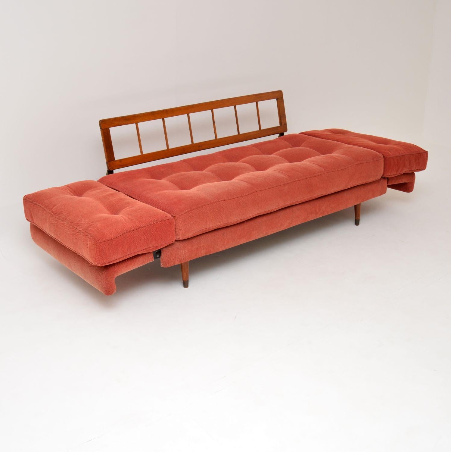 This is a beautiful and extremely comfortable vintage sofa bed, dating from the 1950s-1960s. It was recently re-upholstered by the previous owner in this gorgeous and amazing quality pale pink fabric. The arms lift up and drop to to open this out,