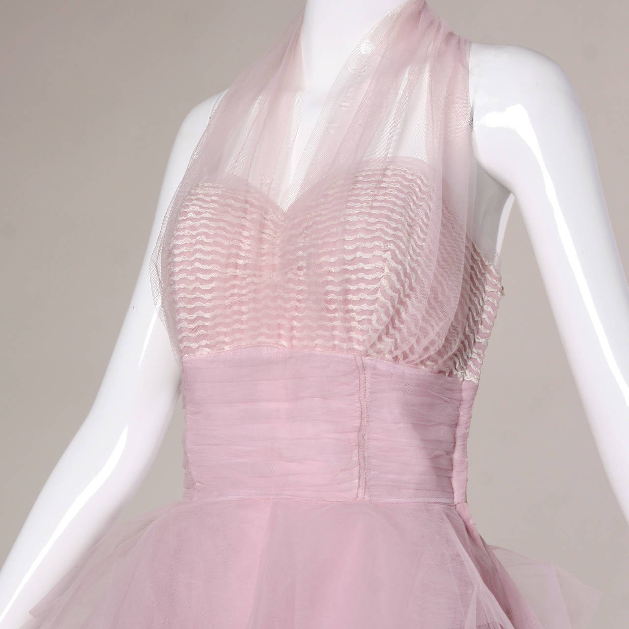 Very 1950s tulle formal dress with a poofy tiered skirt and halter neckline. 

Details:

Fully Lined
Side Metal Zip Snap and Hook Closure
Marked Size: Not Marked
Estimated Size: Small
Color: Pastel Pink-Purple/ White
Fabric: Tulle
Label: Not