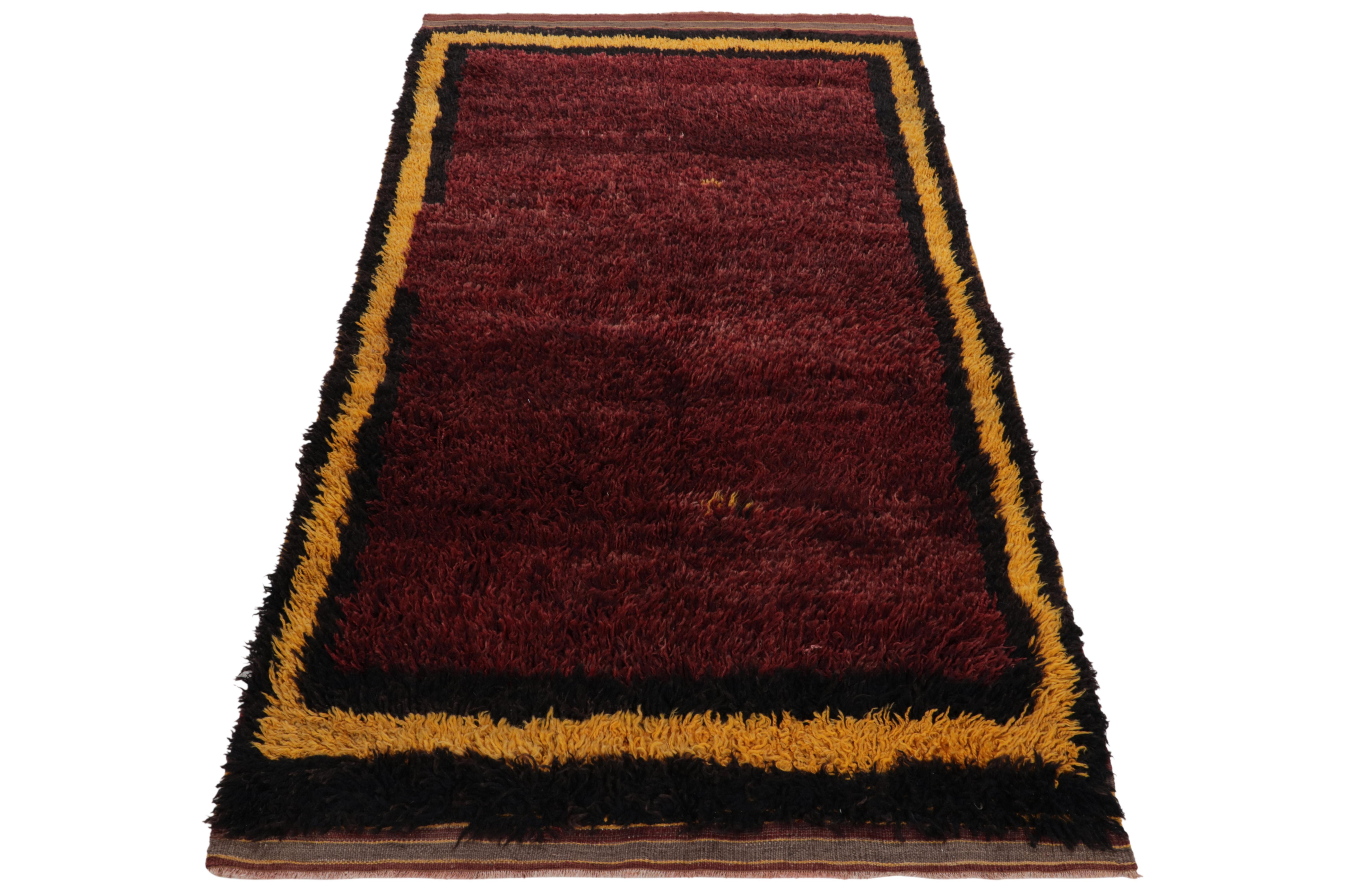 Hand-knotted in wool, a 4x7 vintage Tulu rug originating from Turkey circa 1950-1960, now joining Rug & Kilim’s Antique & Vintage collection. The healthy pile enjoys a solid maroon open field cocooned in alternating black & yellow borders.