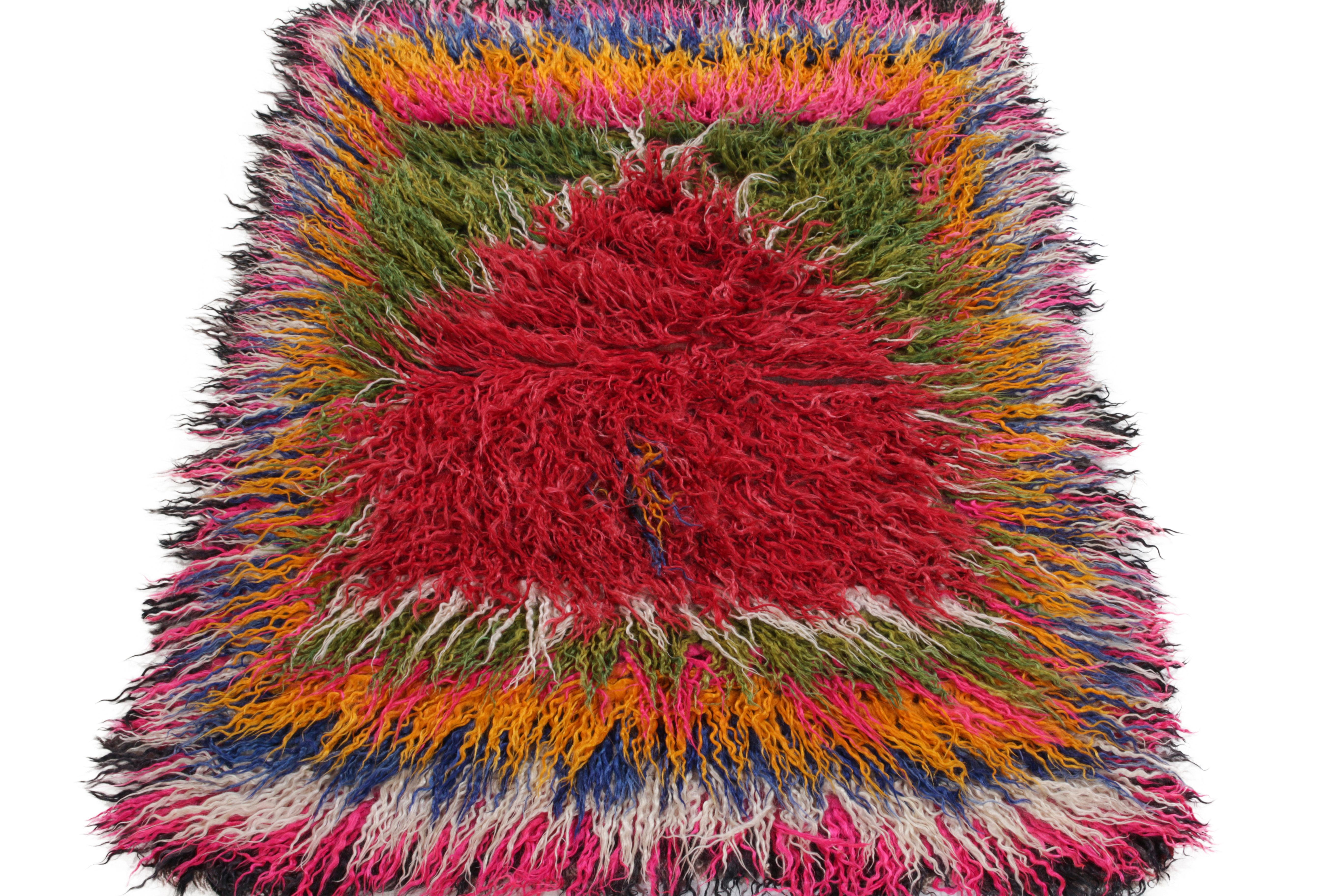 Hand-knotted in wool a 4 x 5 Tulu rug from Rug & Kilim’s Antique & Vintage collection. Originating from Turkey circa 1950s, the tribal piece showcases a shag pile alternating in vivacious tones of red, pink, white, blue, yellow & green connoting
