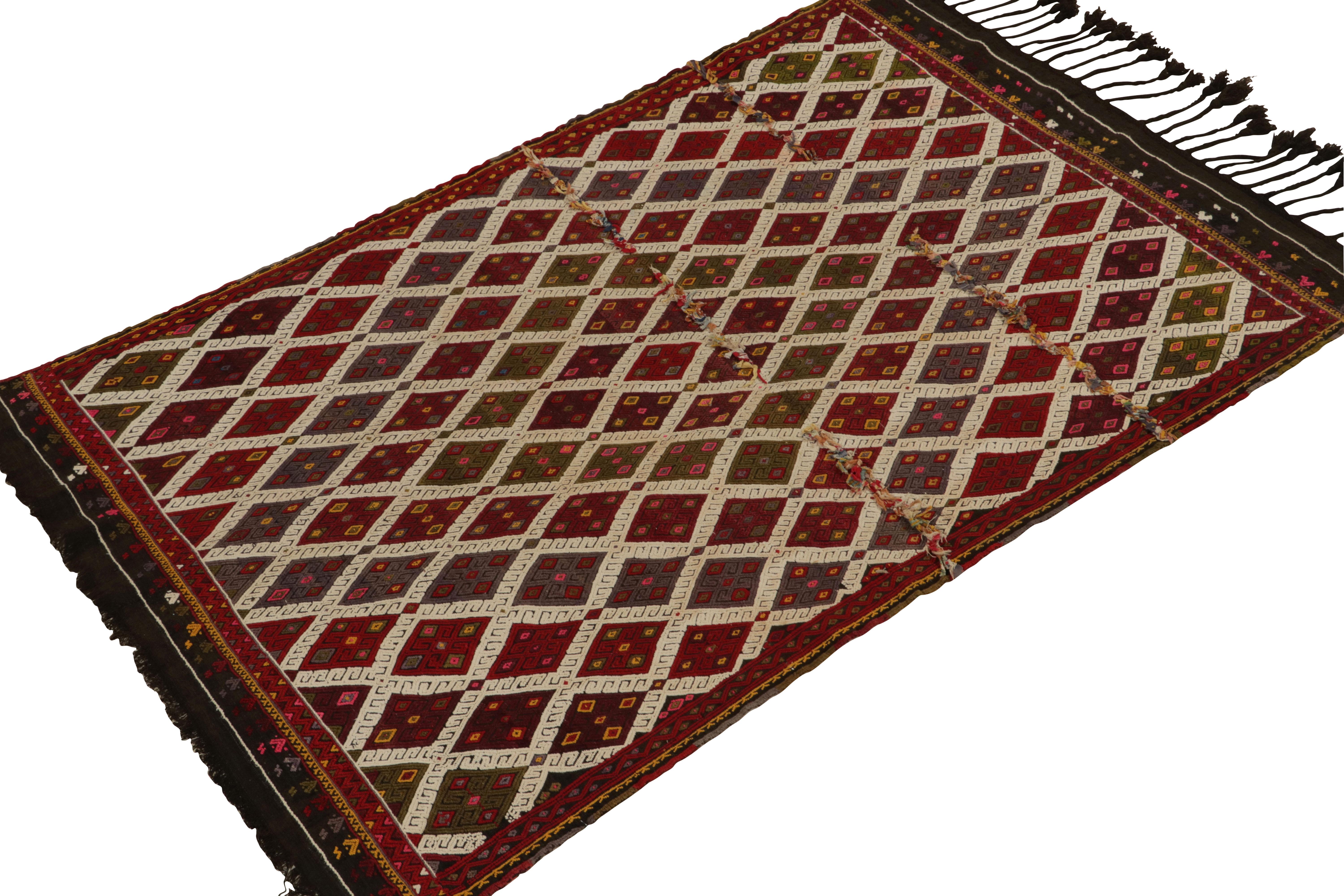 Hand-knotted in wool, a 4x6 vintage Tulu tribal rug drawing on Turkish kilim geometric sensibilities. Originating from Turkey circa 1950s, the midcentury piece enjoys a rich play of mature brown, red, blue & green with white detailing further