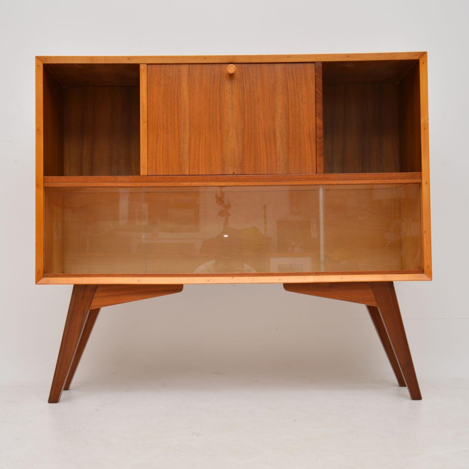 A beautifully made and unusual vintage cabinet in walnut, this dates from the 1950s. It is multi functional, with a built in pull down writing bureau section and bookcase compartments, this would also function well as a tv unit. We have had this