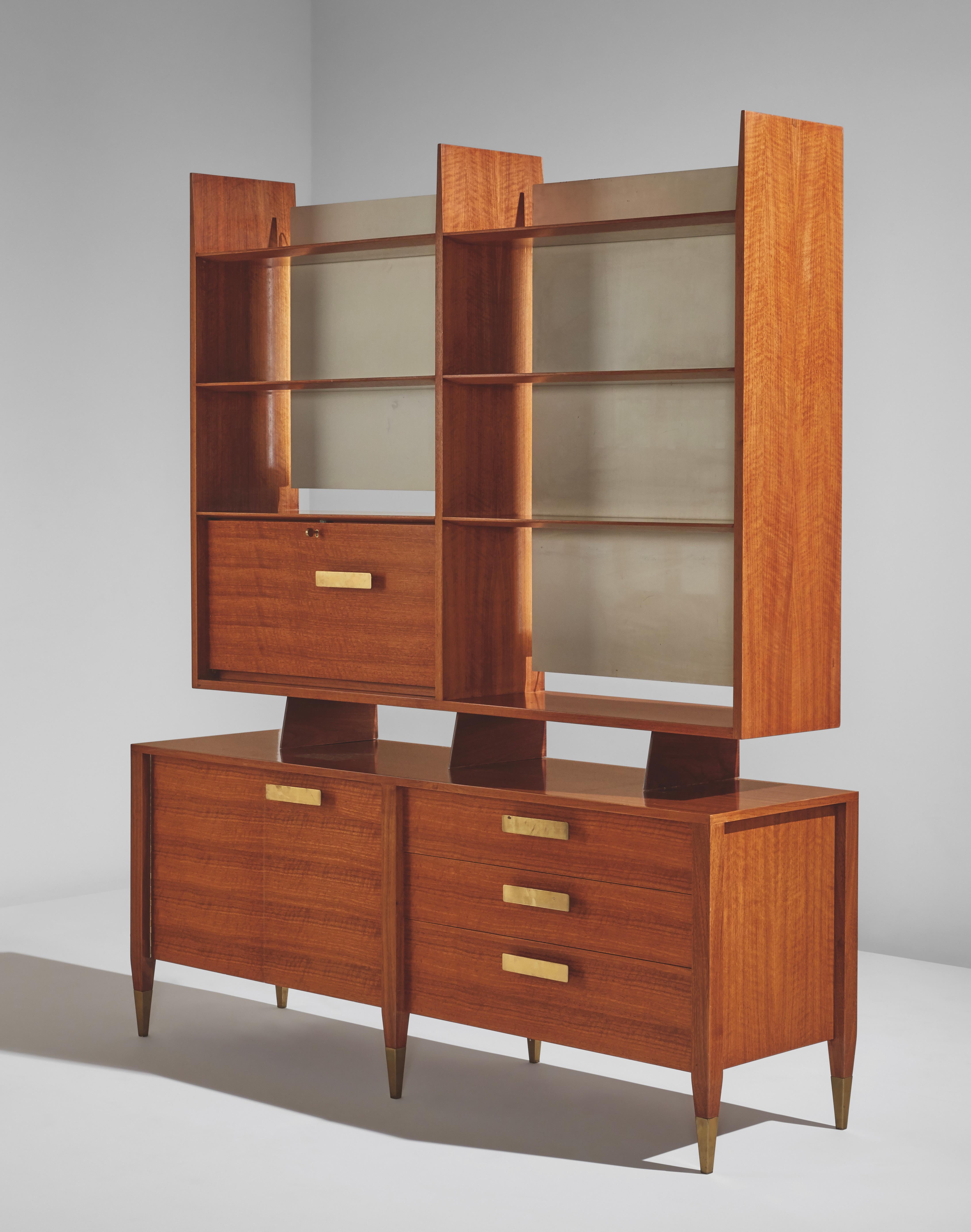 From the 'Modern by Singer' series for Singer & Sons, early 1950s
Rare tall cabinet in walnut, the shelving in the upper section backed by soft white lacquered panels concealing updated electrical light sources, with brass handles and sabots on