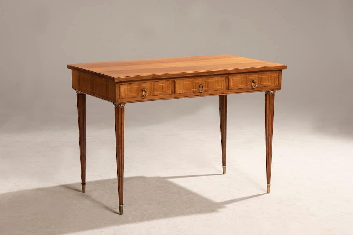 Mesa escritorio de nogal de los años 50 realizada en estilo Luis XVI. 
La parte delantera de la mesa tiene una sección curva. Hay un rosetón en la parte superior y las patas tienen detalles de latón. 
El escritorio está en excelentes