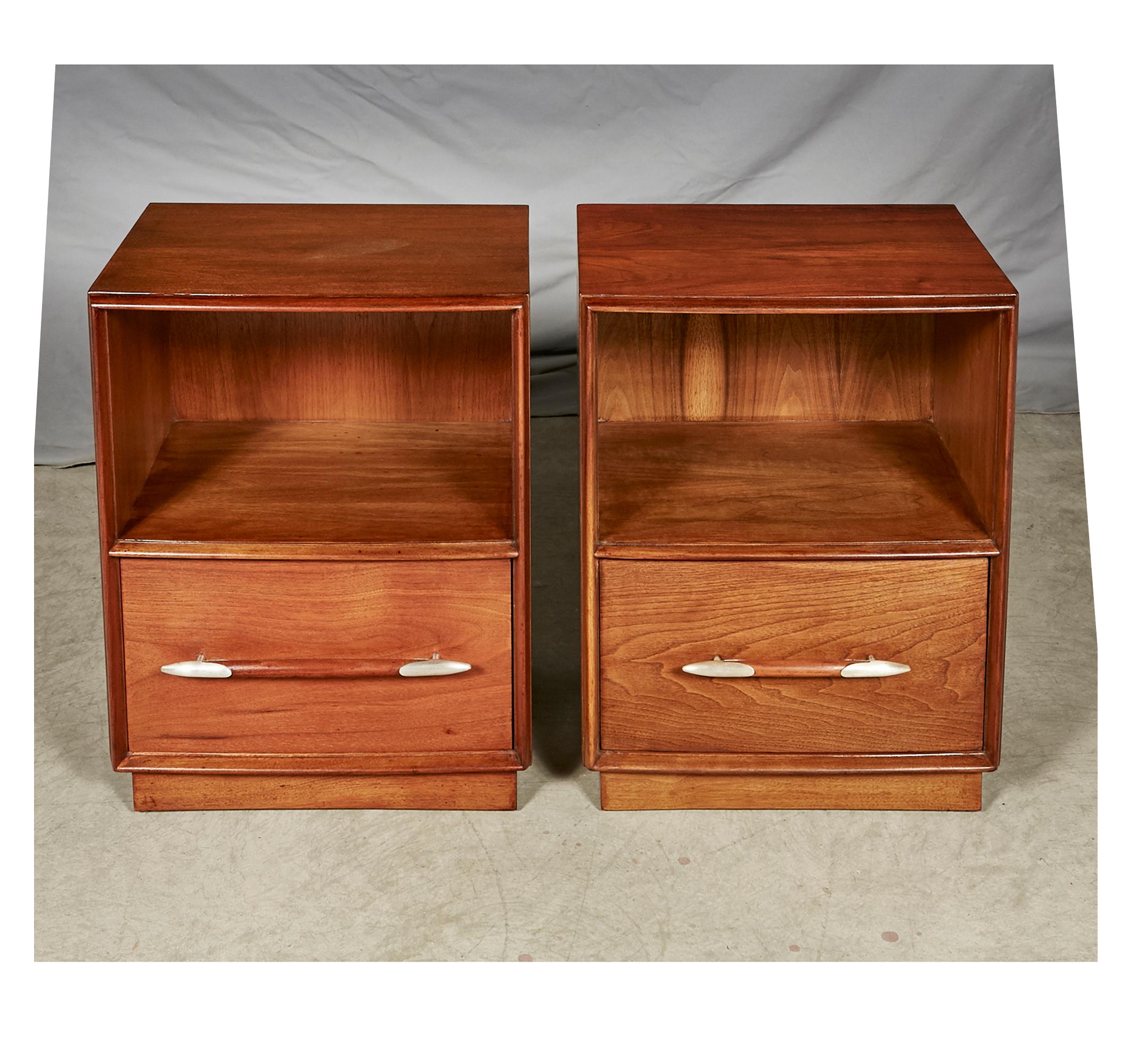 1950s walnut wood pair of nightstands designed by T.H.Robsjohn-Gibbings for Widdicomb Furniture Co. The nightstands have a silver metal accent on the pulls. Fully restored condition, with a small repair to the back of one nightstand. Marked.