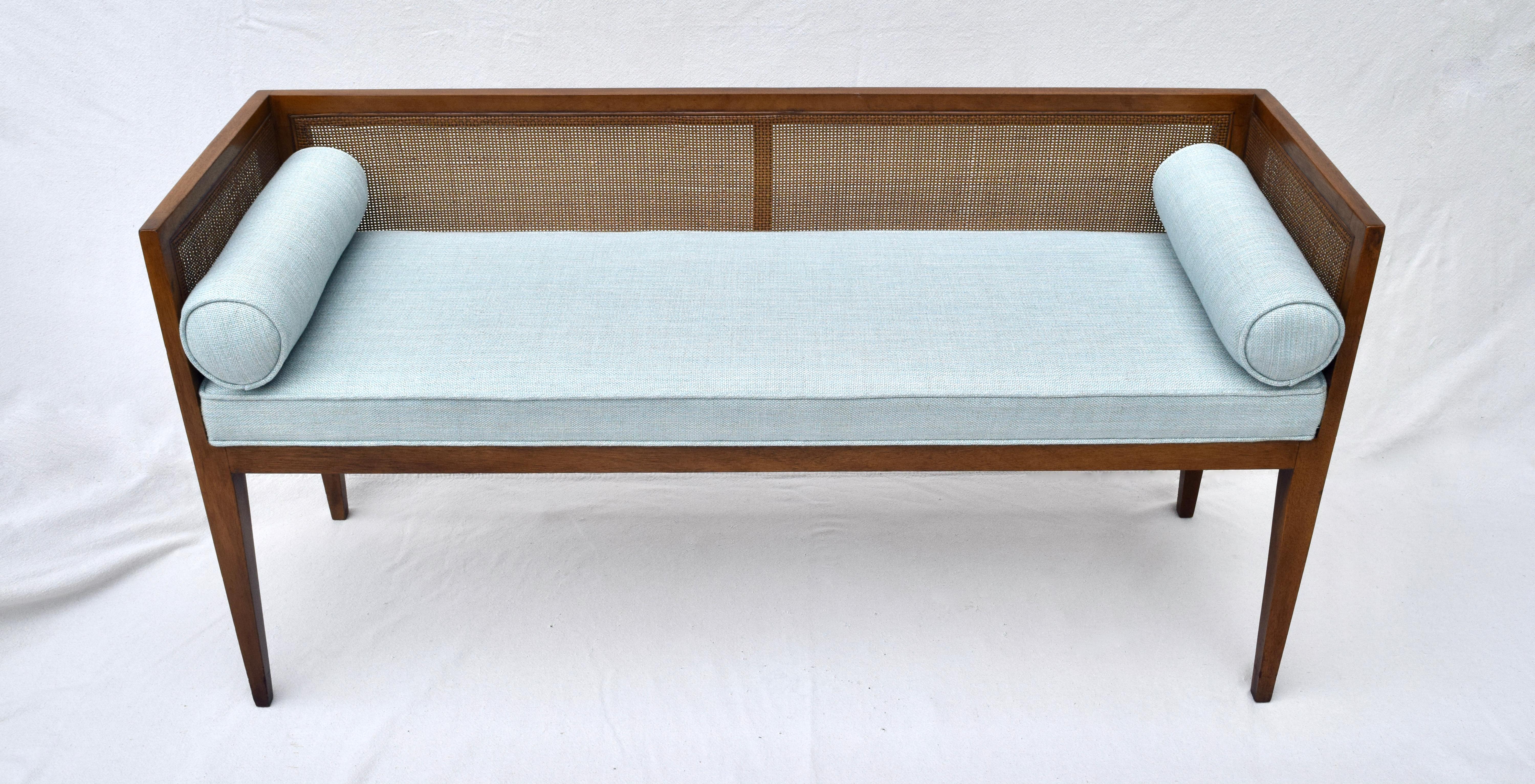 Solid walnut Mid-Century Modern window bench or settee attributed to Edward Wormley for Dunbar. Lithe line design constructed of walnut frame with original fine scale caning. Fully detailed original finish. New restored seat and bolster cushions are