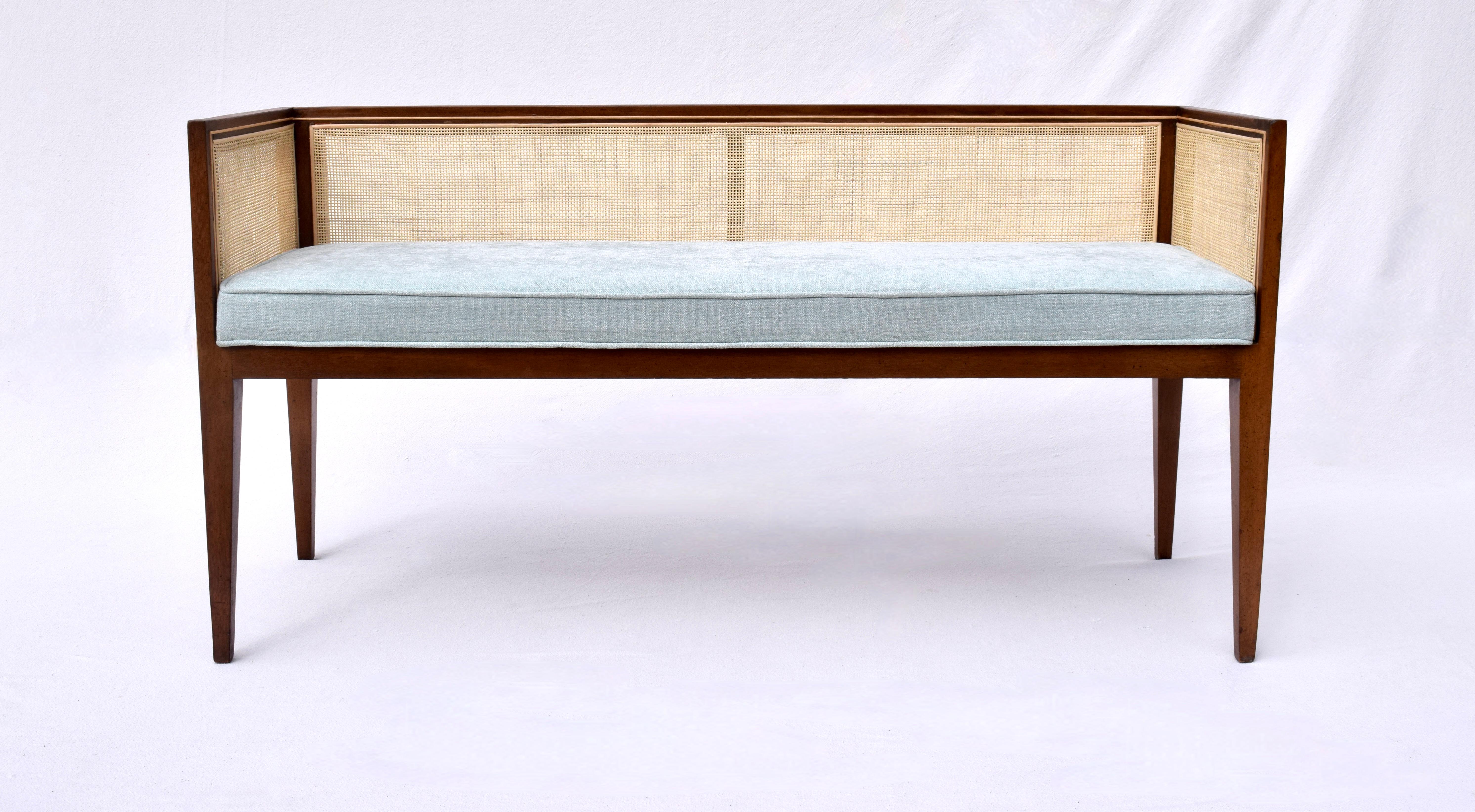 A solid walnut Mid-Century Modern window bench or settee attributed to Edward Wormley for Dunbar. Lithe line design constructed of fully restored walnut frame with new fine scale caning, seat and bolster cushions upholstered in soft blue cotton