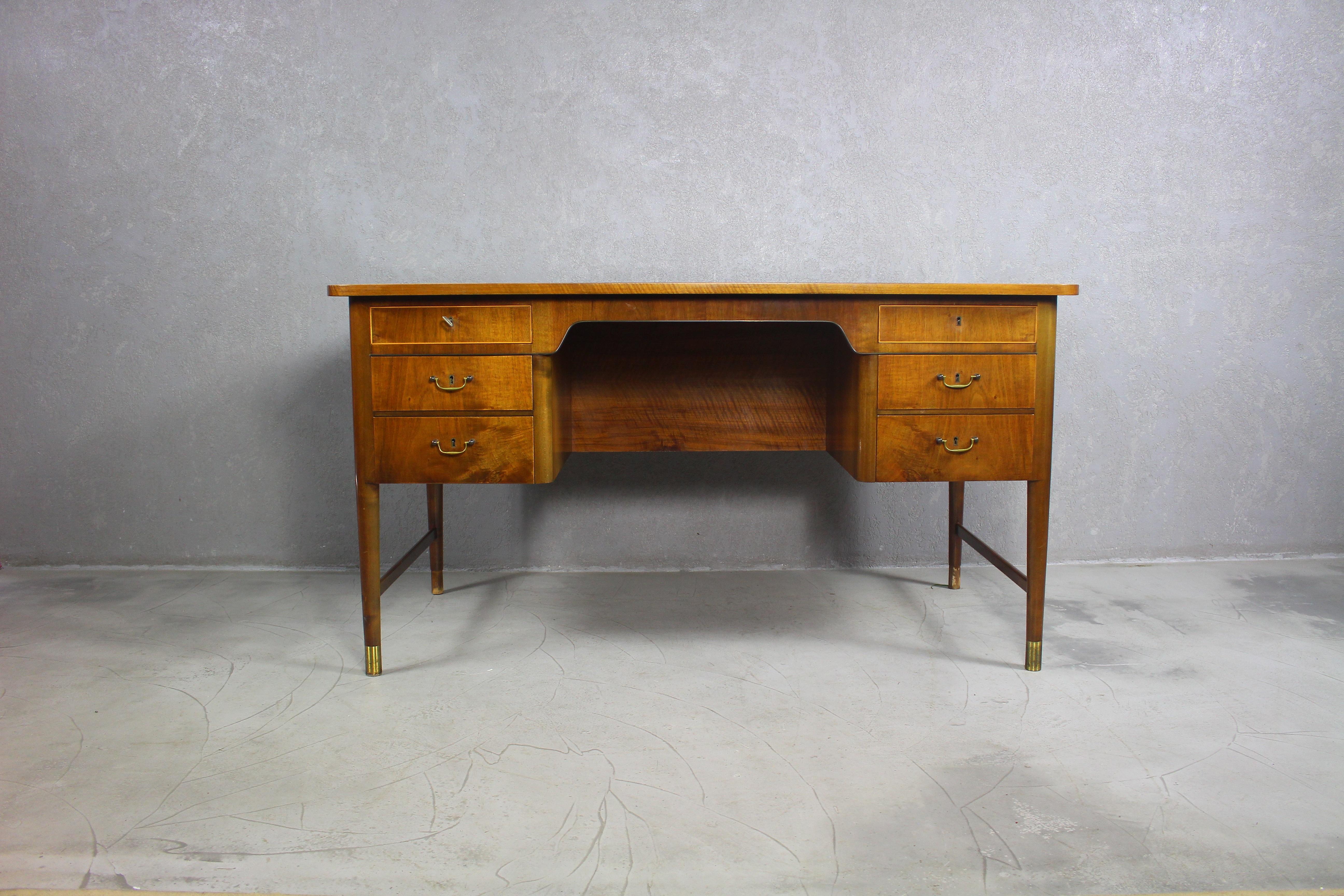 Elegant varnished desk with brass foots and hadles.
The sides of the desk are oval.
Features six drawers. Four drawers decorative brass handles. 

