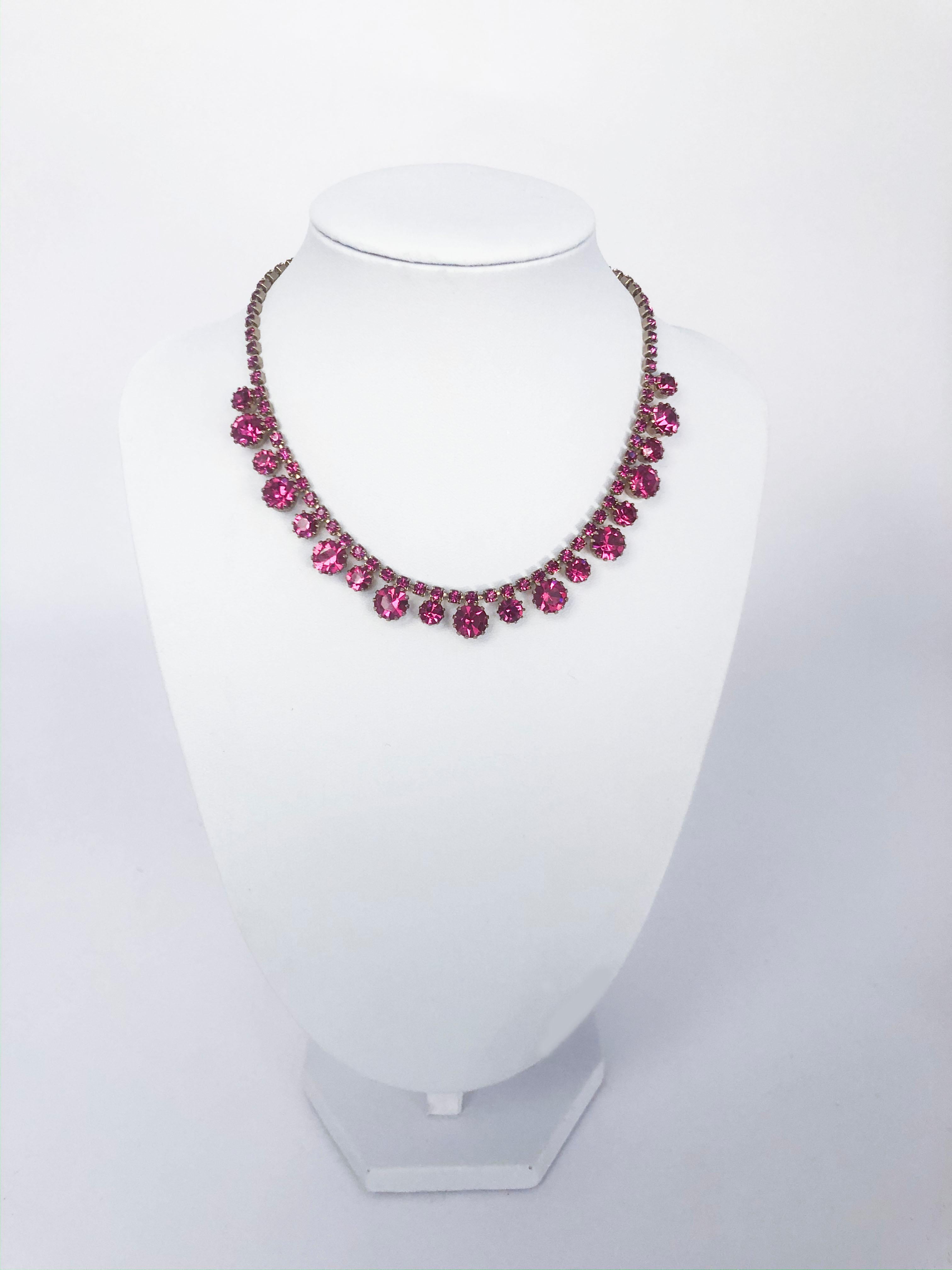 1950's Weiss necklace and earring set featuring large, medium, and small cut rhinestones in hot pink. The clip-on earrings are in a clover shape featuring matching rhinestones and the setting metal for this set has a gold wash. The necklace has a
