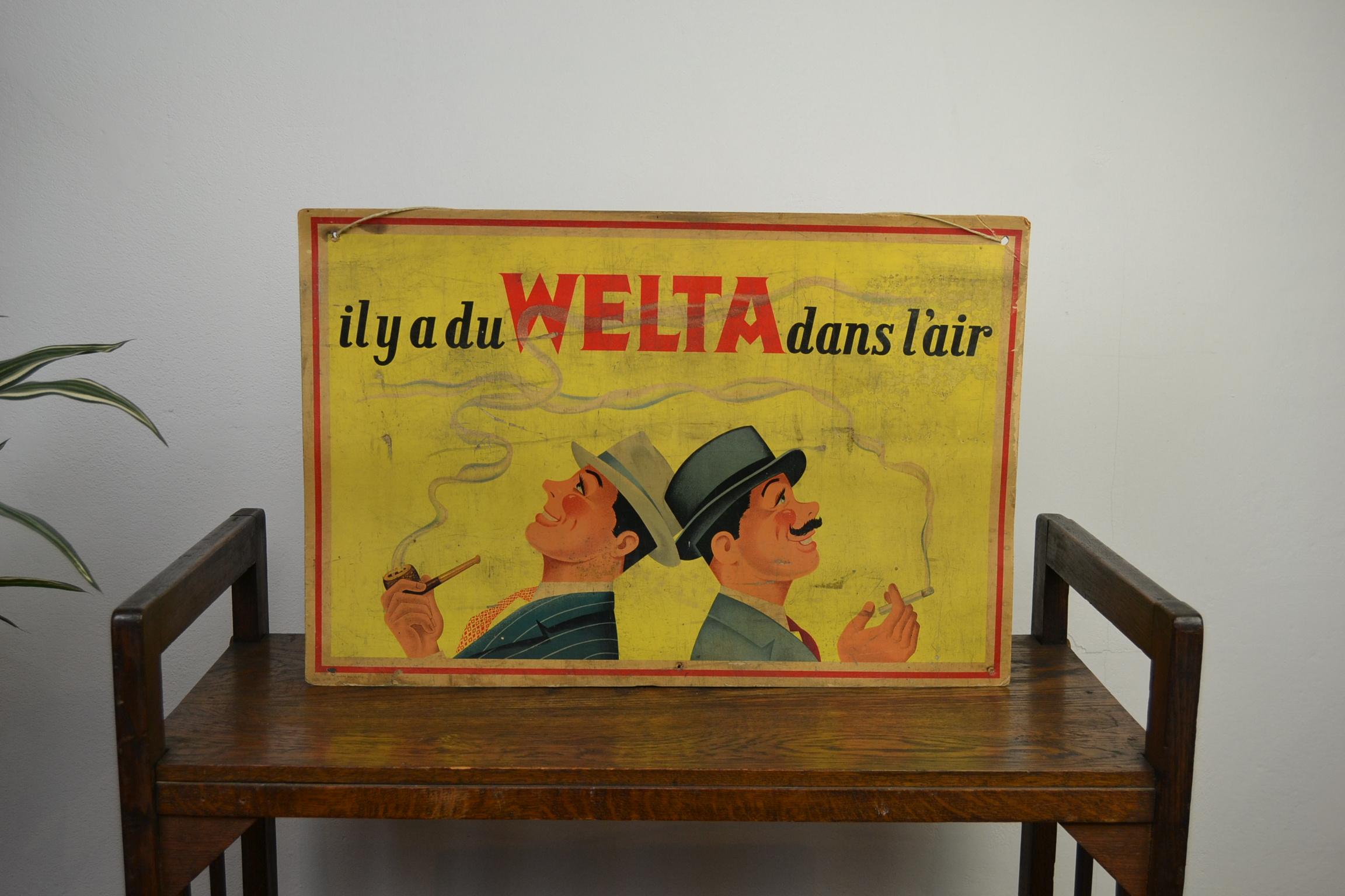 1950s Welta Tobacco Advertising Sign . 
This Belgian Tobacco Sign has a great design : 
2 gentleman in suit wearing a tie and hat and smoking a pipe and a cigarette with WELTA Tobacco . There is some nice smell in the air , Welta Tobacco . 

This