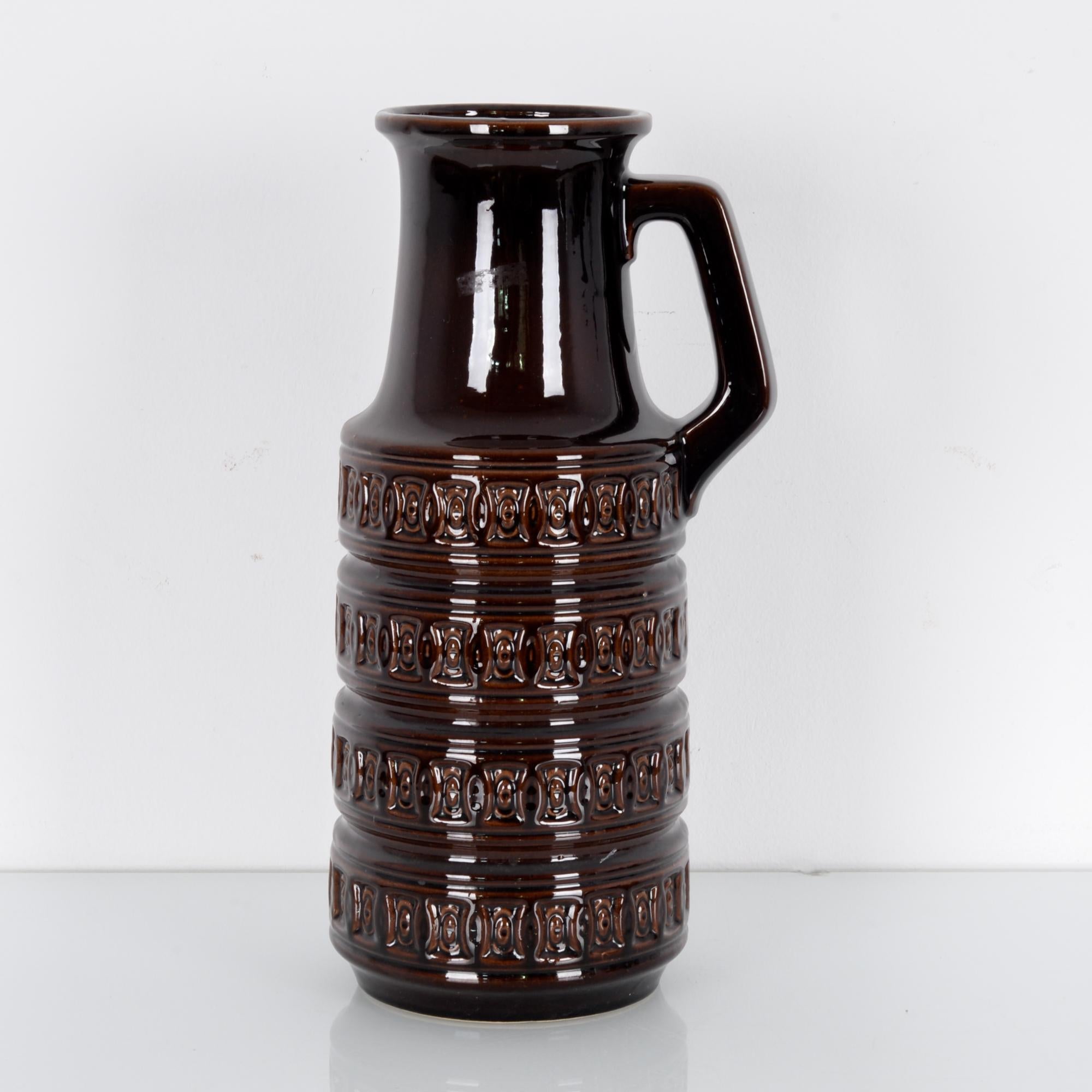 A ceramic vase produced in West Germany, circa 1950. This handled vase coated in brown glaze stands at 45 cm tall. Art pottery was a flowering movement in midcentury West Germany, here characterized by the engraved pattern, thick layer of glaze, and