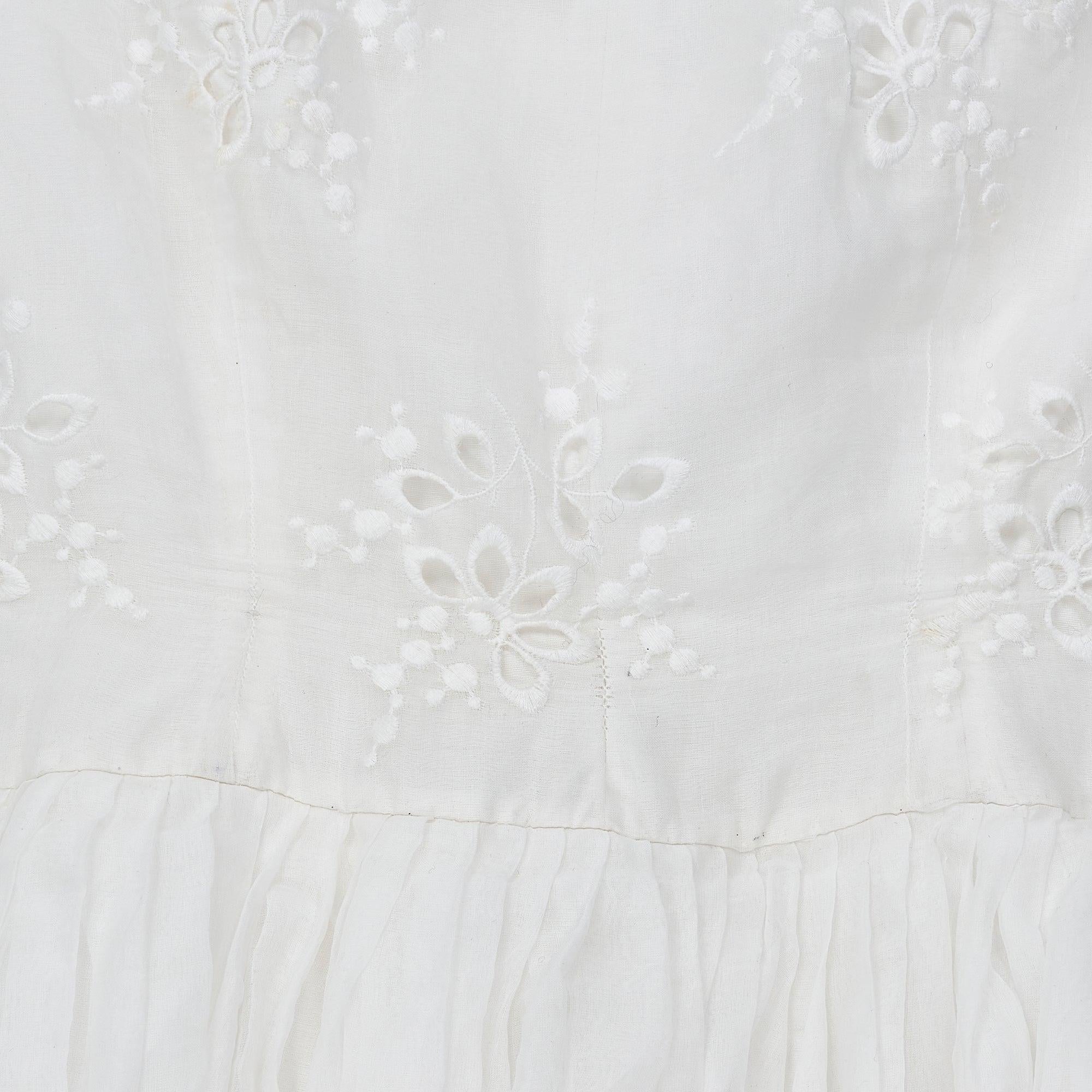Questo abito da sposa anni '50 di produzione francese è realizzato in organza di cotone bianca di alta qualità.  Realizzato secondo una classica silhouette anni '50, con una vita stretta e una gonna ampia che avvolge le gambe e termina intorno alla