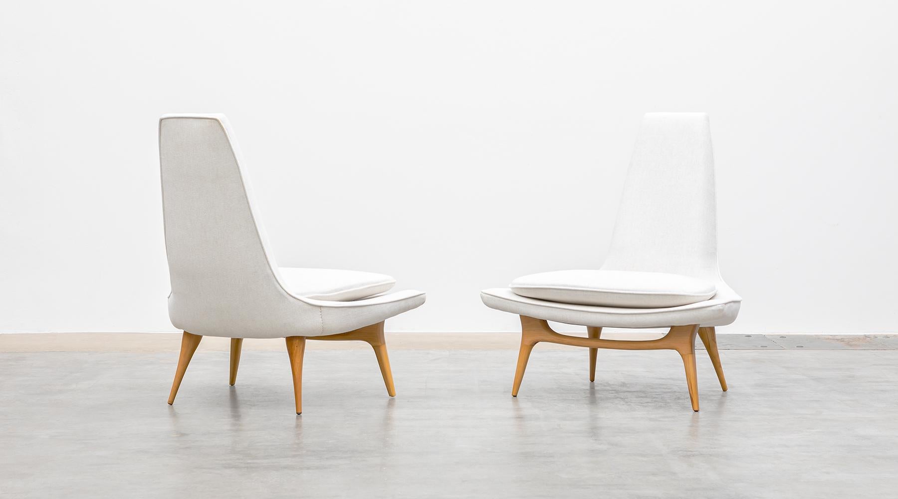Matching pair of lounge chairs, white fabric, new upholstery, USA, 1950s.

Sculptural pair of lounge chairs by Karpen, circa early 1950s. These lovely examples have subtly curved seats and tall tapered backs with beautifully formed light wooden