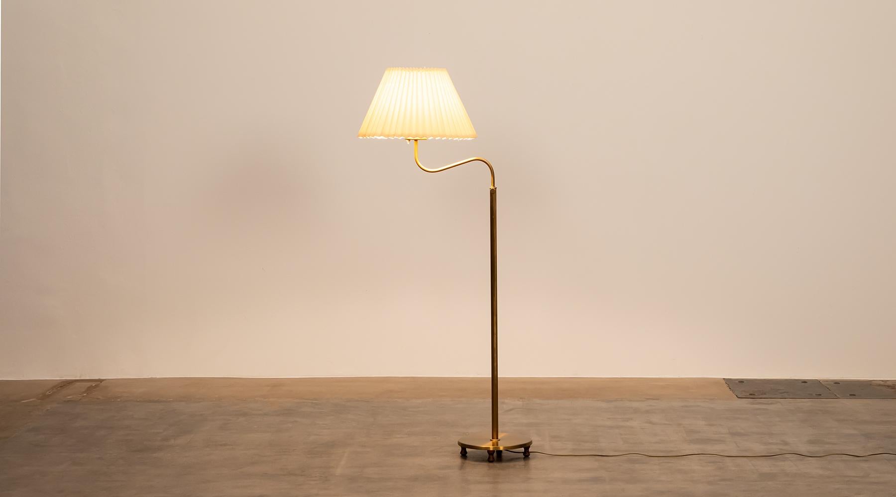 Floor lamp by Josef Frank, brass stem and off white fabric shadow, Sweden, 1950s.

Lovely floor lamp with a sturdy yet elegant brass rod, whose neck elegantly disappears into the lampshade. The lampshade is accurately folded all around and has a