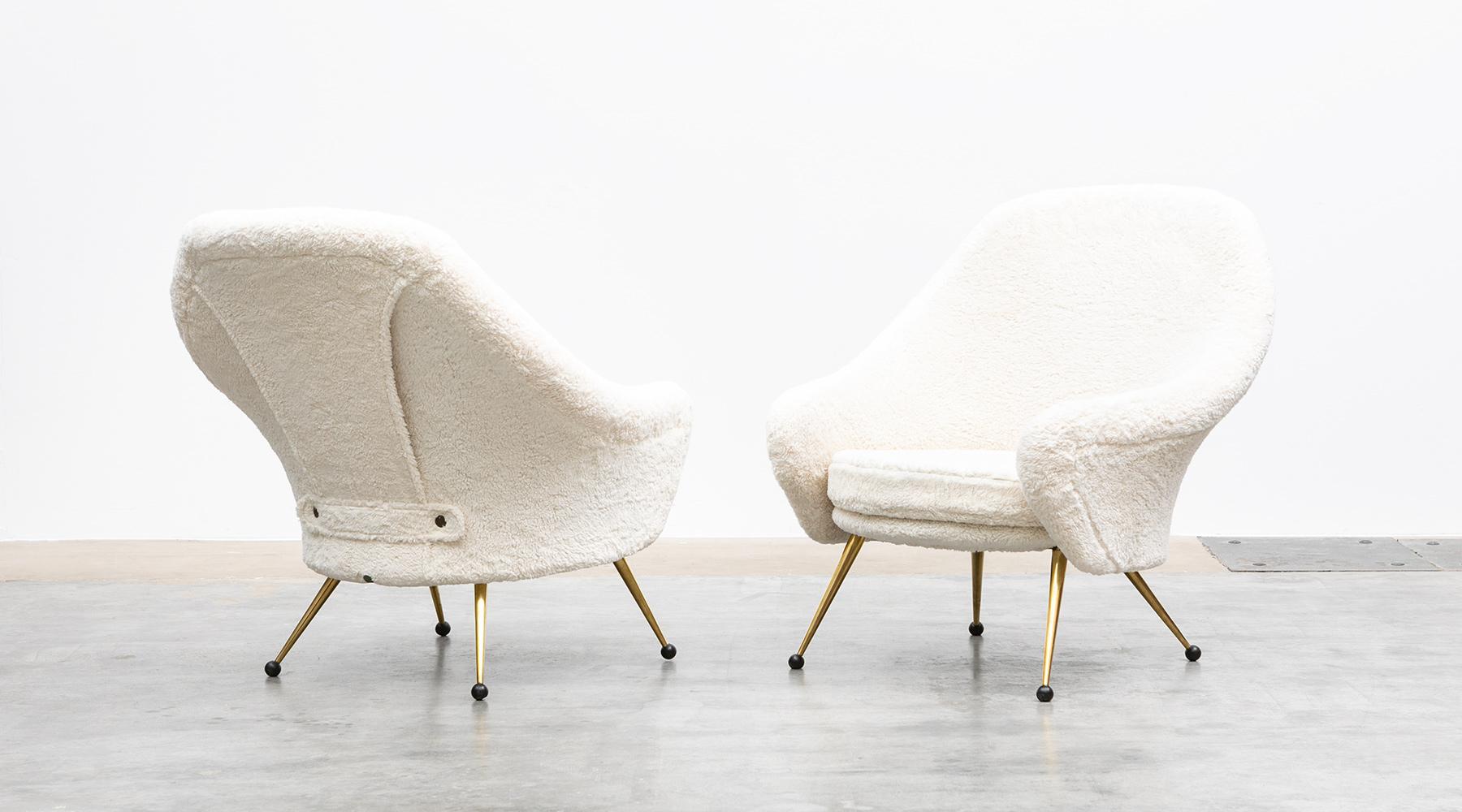 This beautiful couple of lounge chairs designed by Marco Zanuso comes on four brass legs. The seat and the back of the chairs are covered with beige high-quality faux fur with a nice worked detail at the back. The chairs provide exquisitely