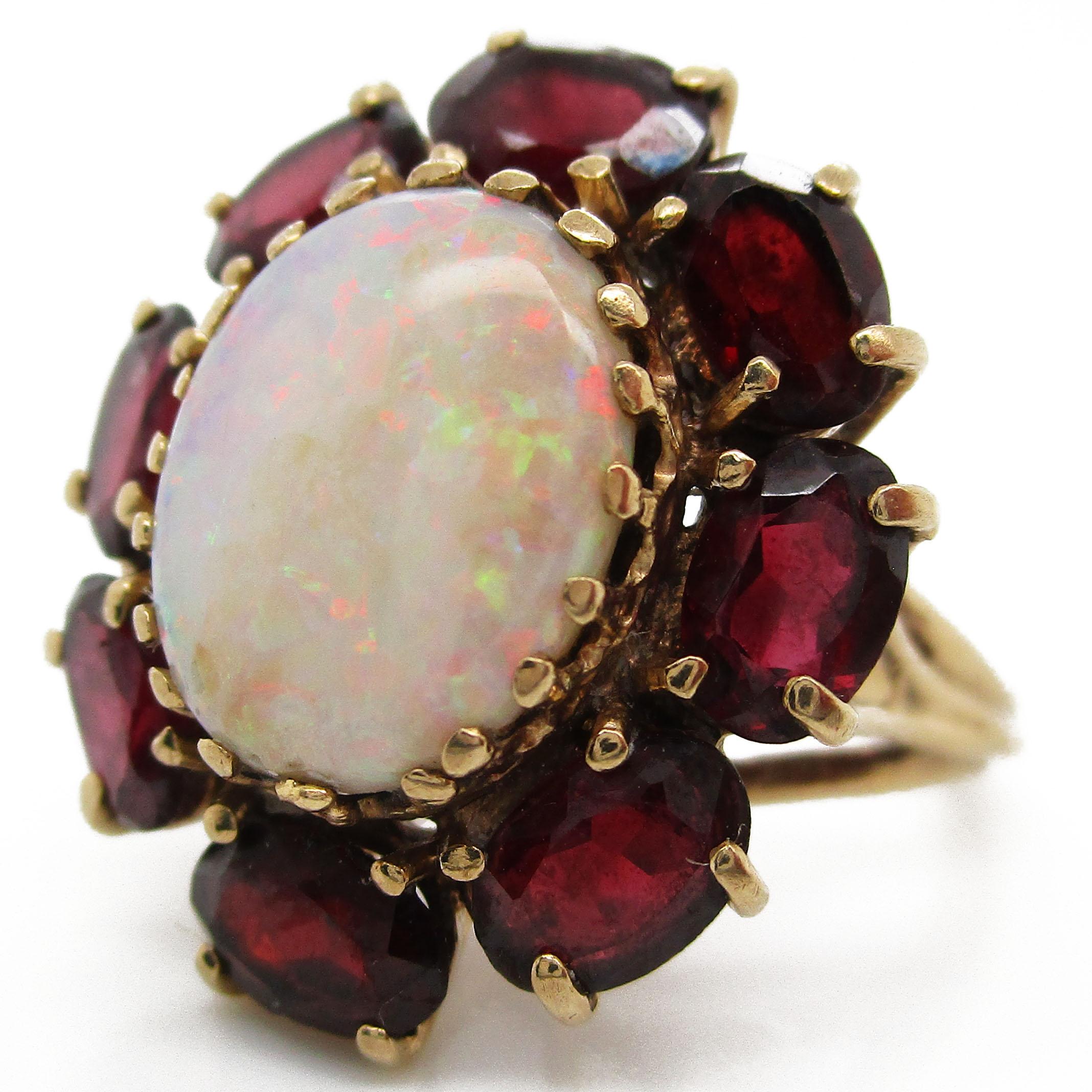 This killer ring is an awesome 1950's design! The ring is 14 karat yellow gold with a white opal centerpiece (12.75x9.55mm opal). The opal has excellent bright red and green flashes with a smooth and even color play. Said opal is framed by 8