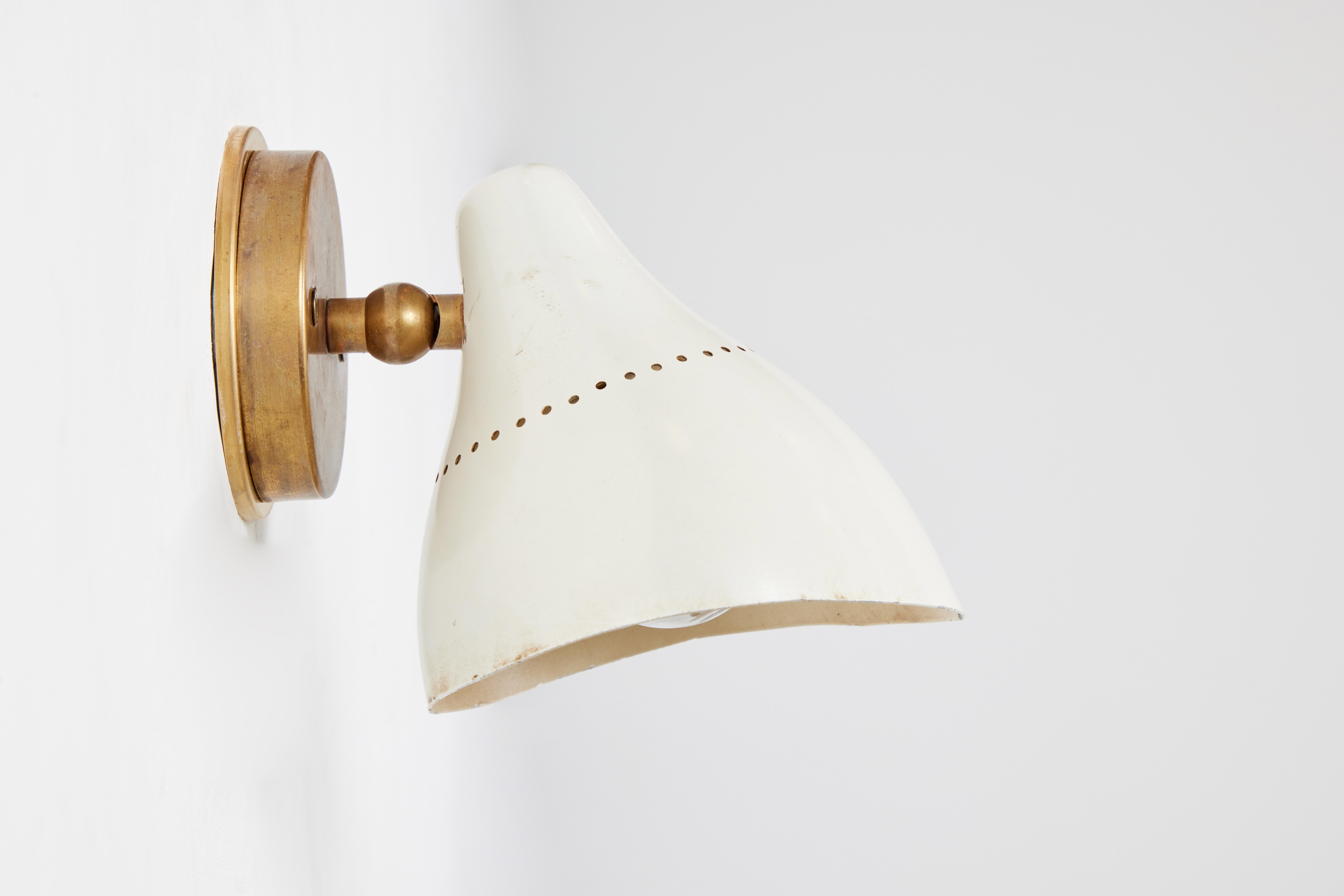 1950s white perforated metal & brass sconce by Stilnovo. Executed in white perforated metal and patinated brass with the trademark Stilnovo circular 'knuckle' jointed brass arm for up/down adjustability. A sculptural and refined design
