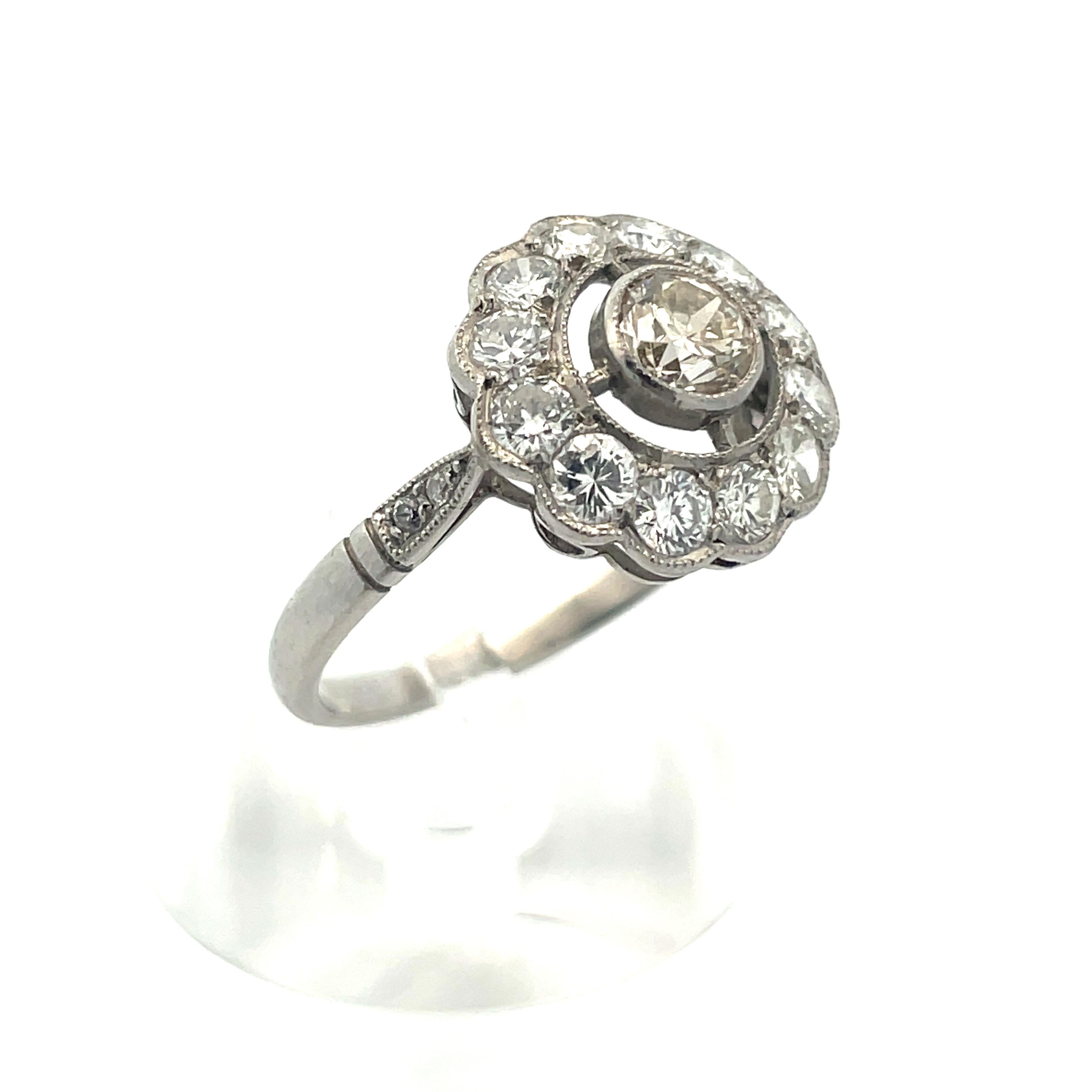 This beautiful French platinum ring features a warm center diamond, surrounded by 12 brilliant white diamonds. The warm center stone, indicative of the period, is a .70 ct VS1 K color diamond. The 1.66 tw VS1 D color surrounding diamonds give this