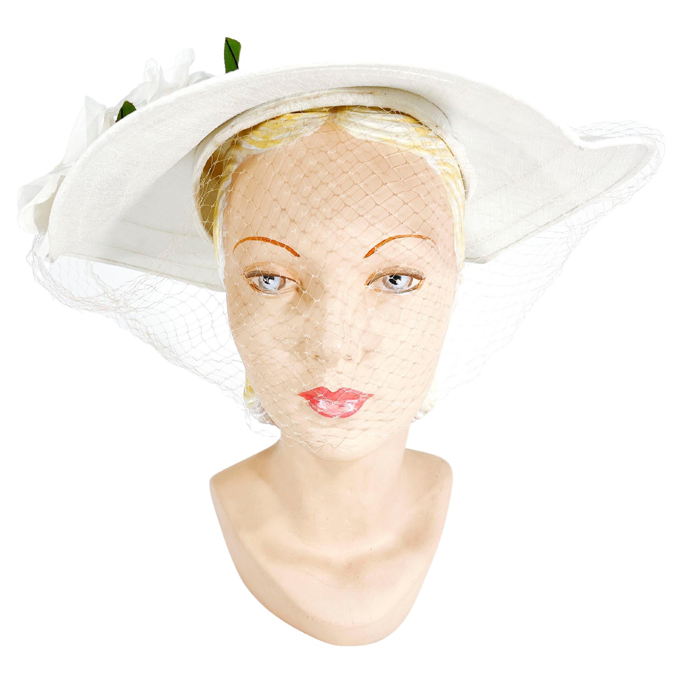 1950s White structured raw silk picture hat trimmed with velvet ribbon and decorated with a double silk rose flowers with rhinestone accents. In addition, the front of the hat has a full-faced veil in a light nude color.