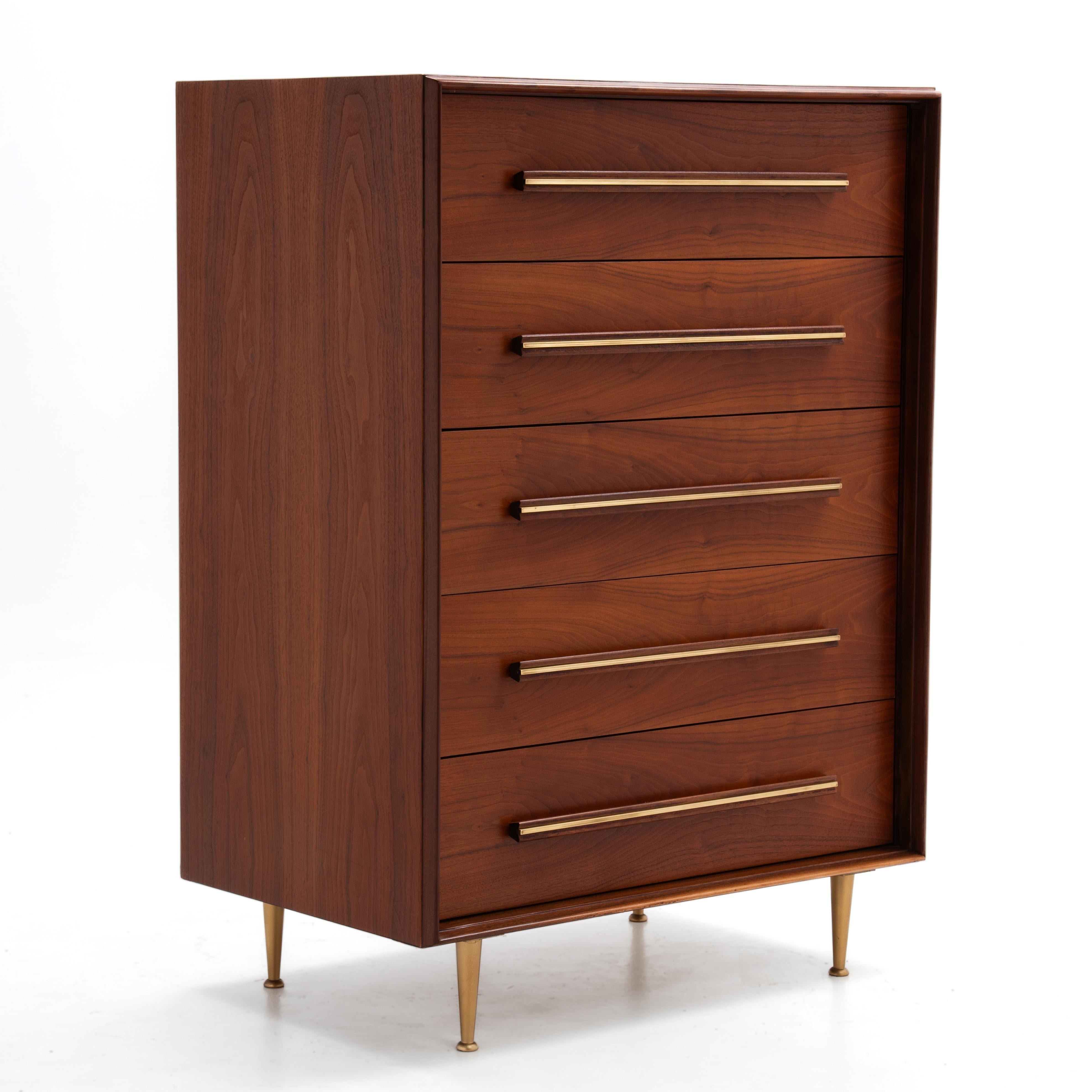 An impressive 1950s tall chest of drawers made by the Widdicomb Furniture Company and designed by T.H. Robsjohn-Gibbings. Perfectly book matched drawers, solid walnut handles, brass inlay and brass toned feet. We have a matching six drawer dresser