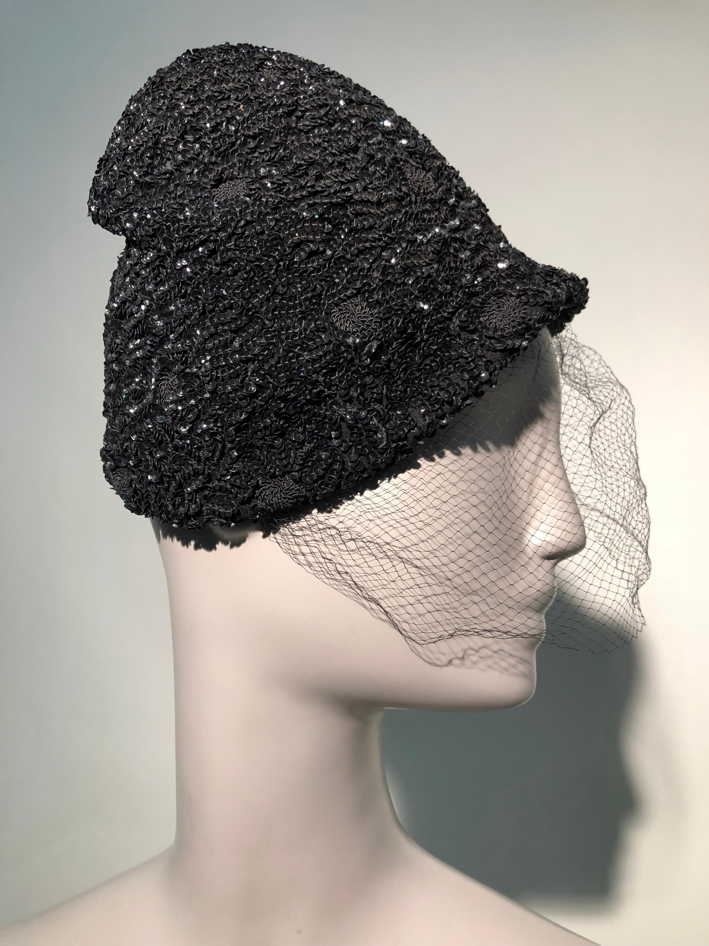 A whimsical 1950s William Silverman peaked and molded cap with a small front bill is completely encrusted with black sequins and completed with a veil.