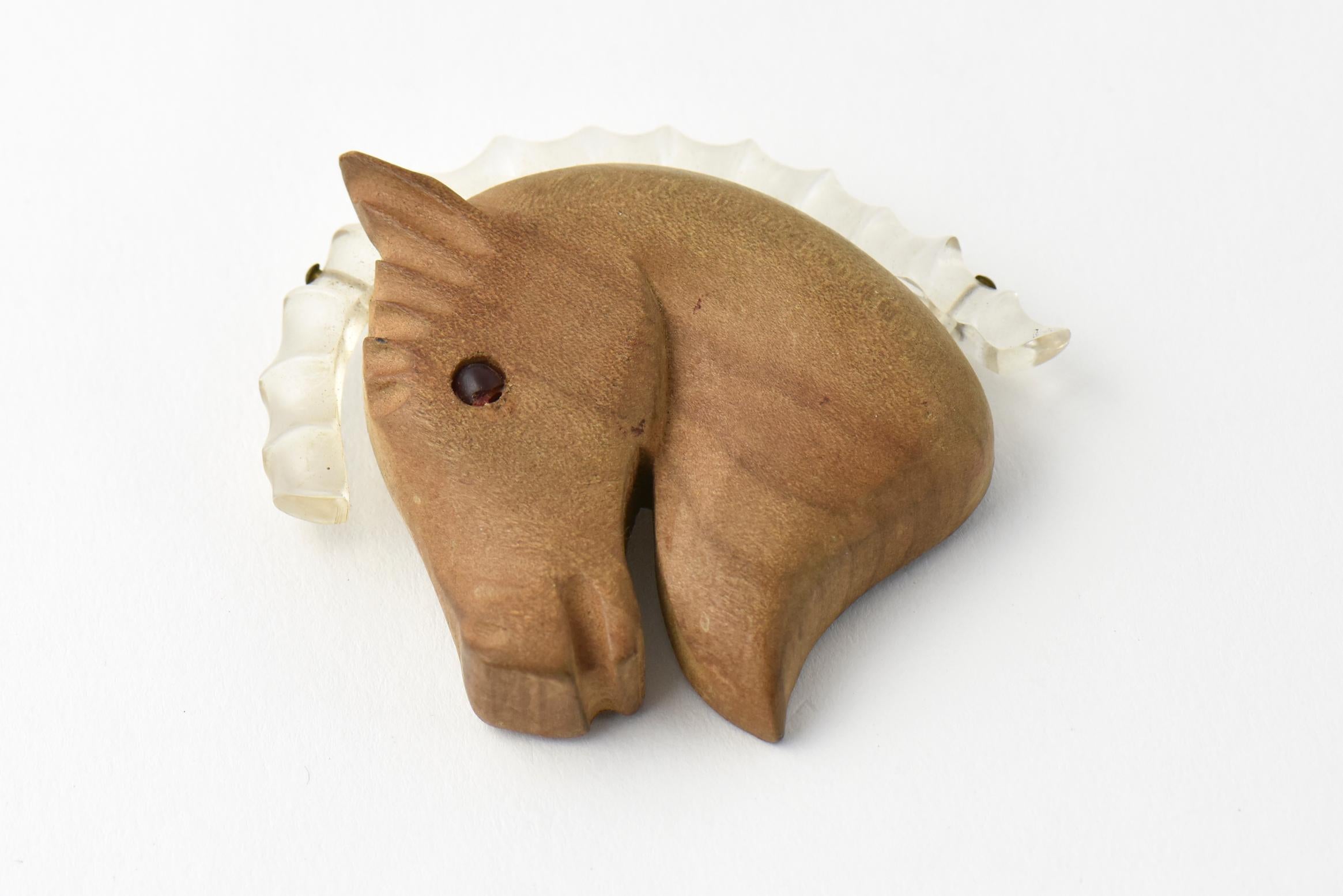 Fabulous Hand Carved Wood and Lucite Brooch. The horse's head is carved wood with a red Lucite eye and clear Lucite Mane. Similar novelty pins can be found in 