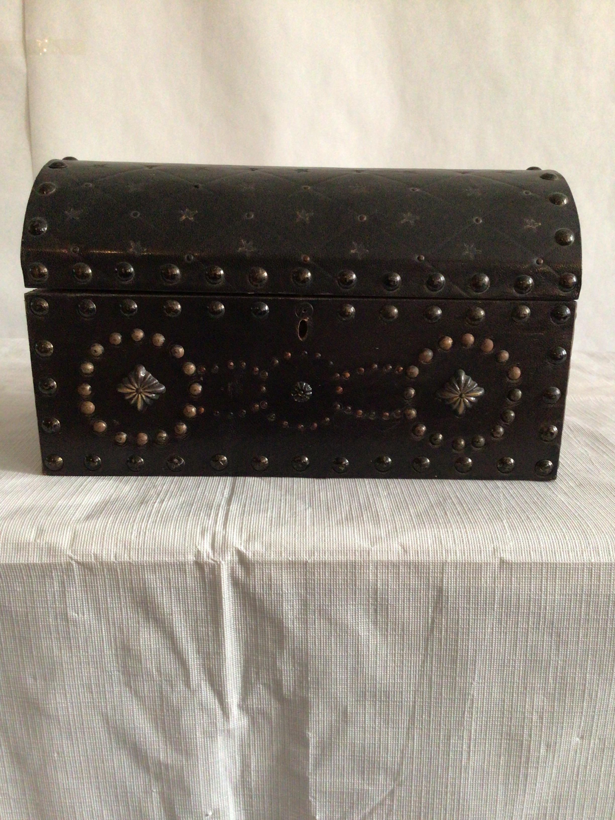 This 1950s wooden box is covered in embossed leather with decorative metal studs. It has a fabric lined interior and key included