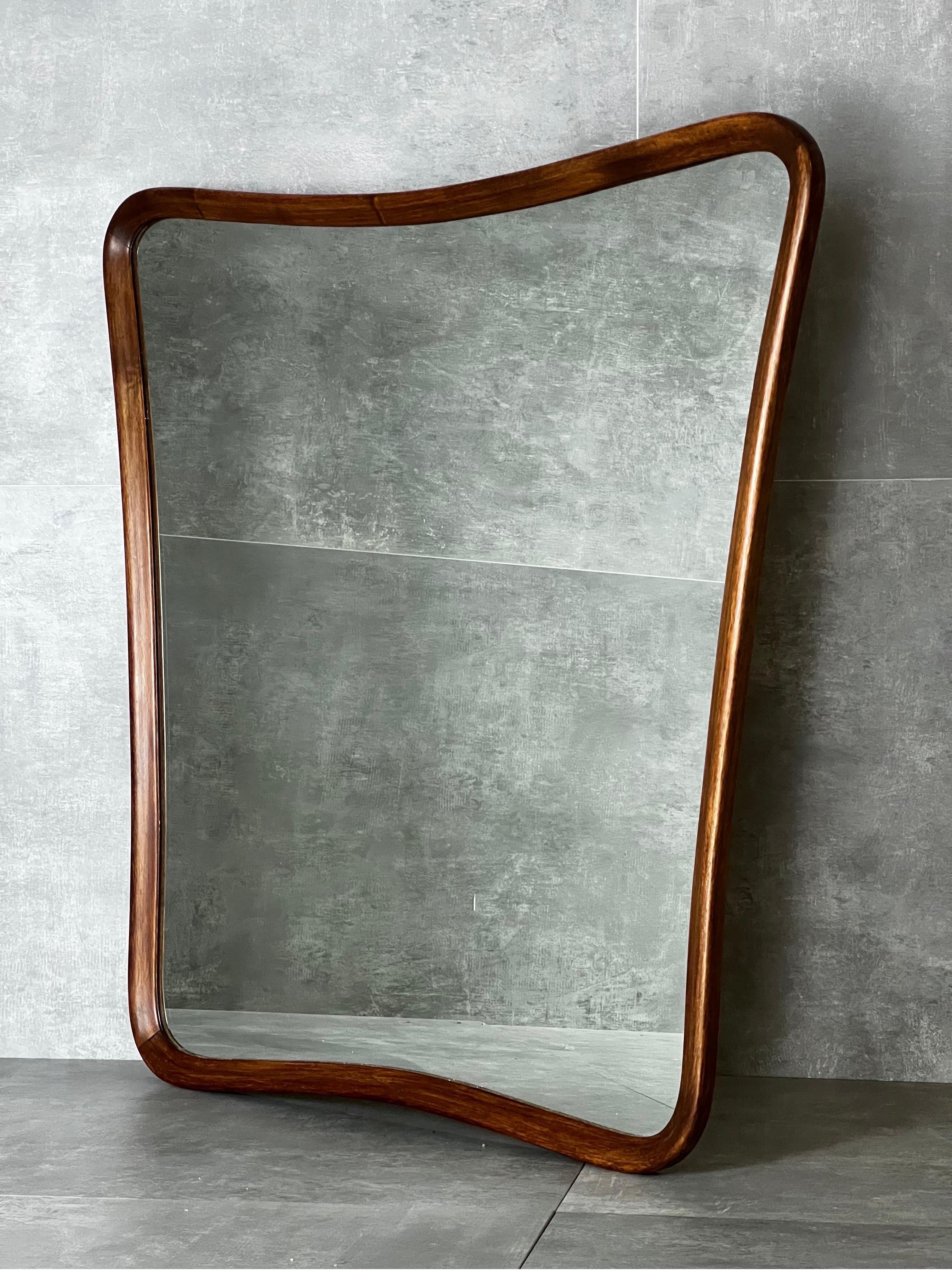 Wall mirror with wooden curved frame designed and manufactured in the 50s.