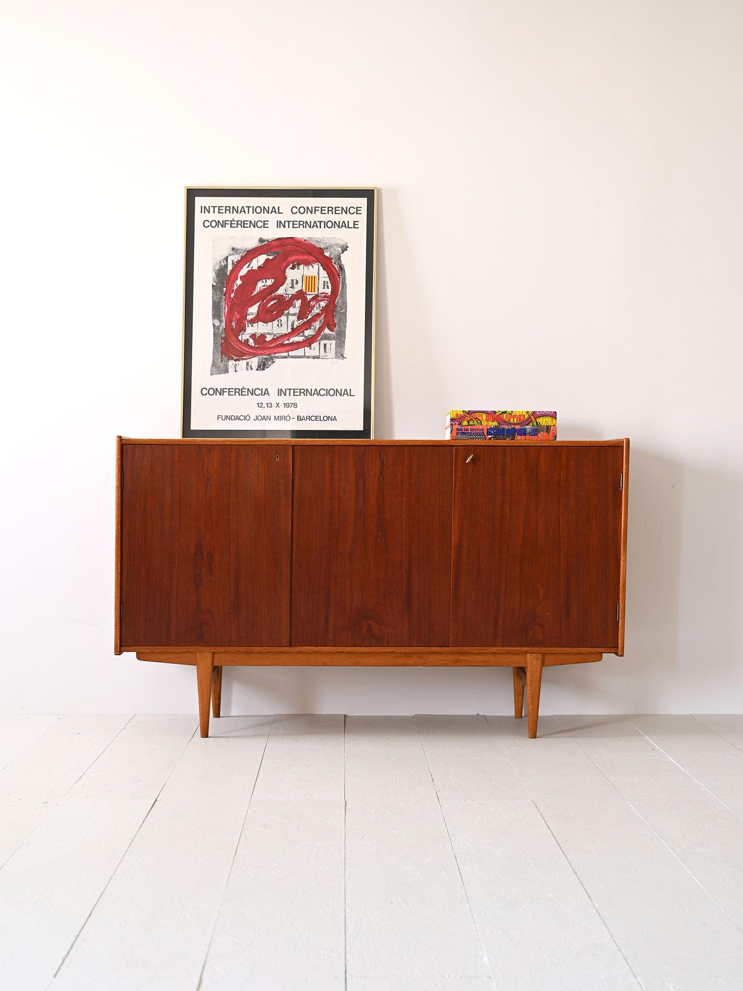 Scandinavian teak highboard with three hinged doors equipped with a lock.

A modern and capacious piece of furniture inside which there are shelves that allow you to divide the space according to your needs.
Ideal as a piece of furniture for the