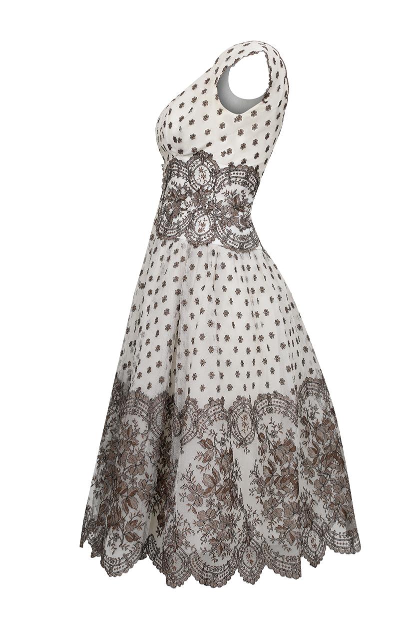 This enchanting 1950s couture dress in ivory and fawn net lace is by the iconic House of Worth's London branch and unsurprisingly, showcases some truly magnificent construction. The dress has a classic 50s prom style aesthetic and features a fitted