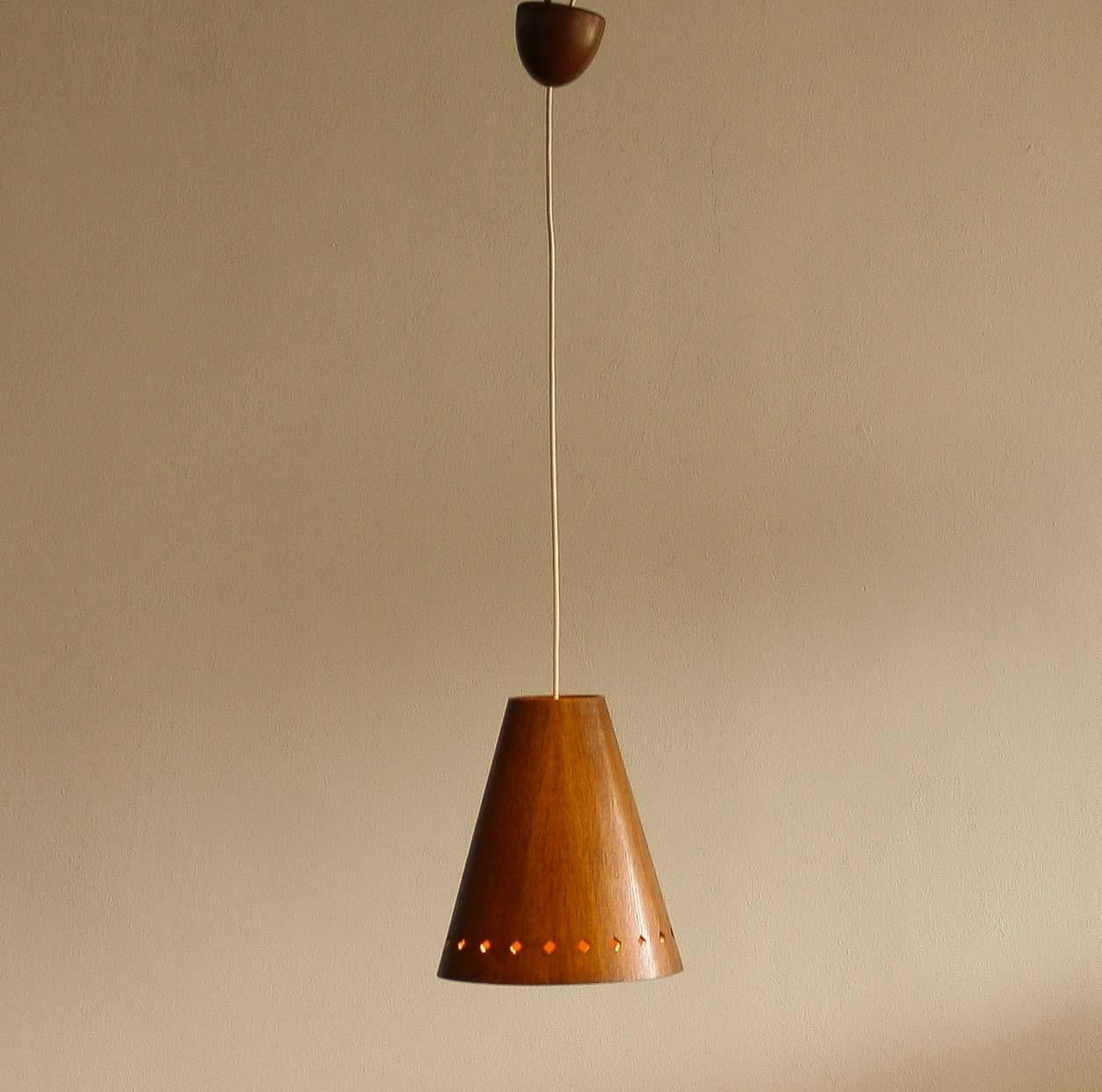 Very nice hanging lamp, model 565, made of wood designed by Uno & Östen Kristiansson for Luxus Vittsjö, Sweden.
The perforation on the shade gives it a beautiful shining.
The lamp is in very good condition.
Period 1950 
Dimension: H 30 cm, Ø 25