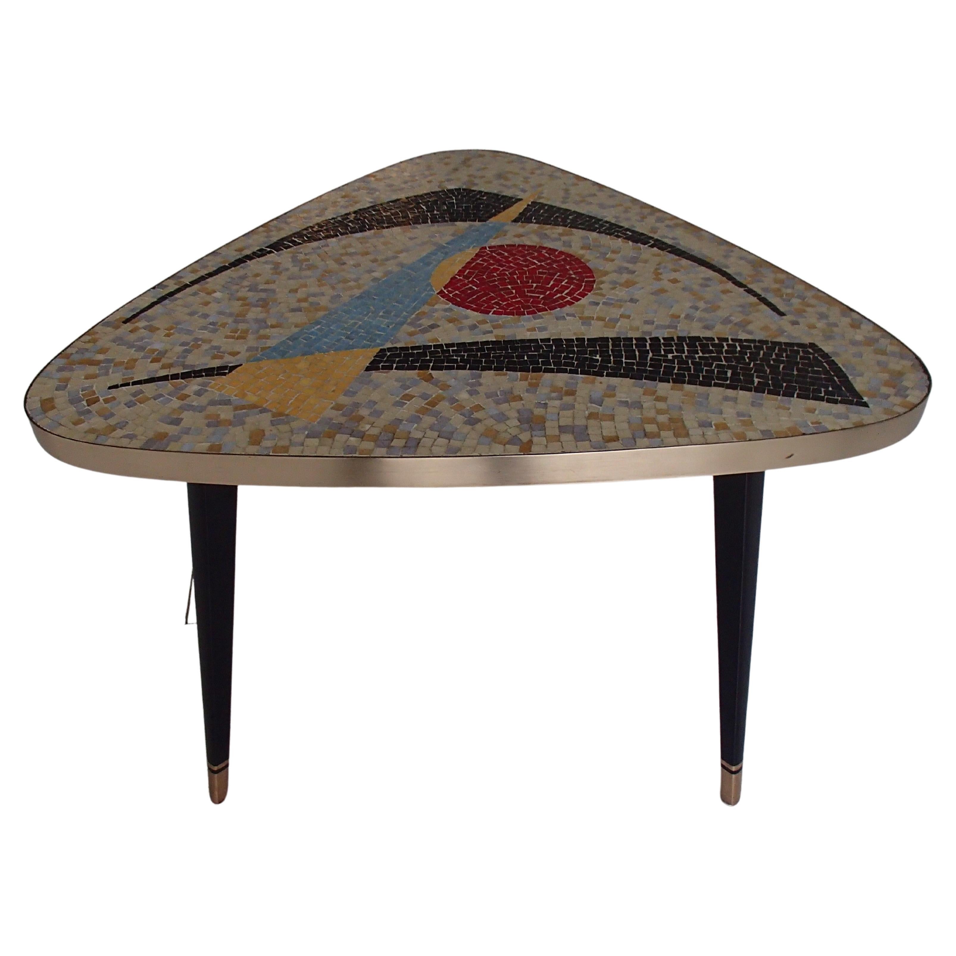 1950thies Triangular mosaic table on 3 streamline black and gold painted legs. On the top mosaic in the manner of Ferdinand Léger with strong colors and surrounded with brass.