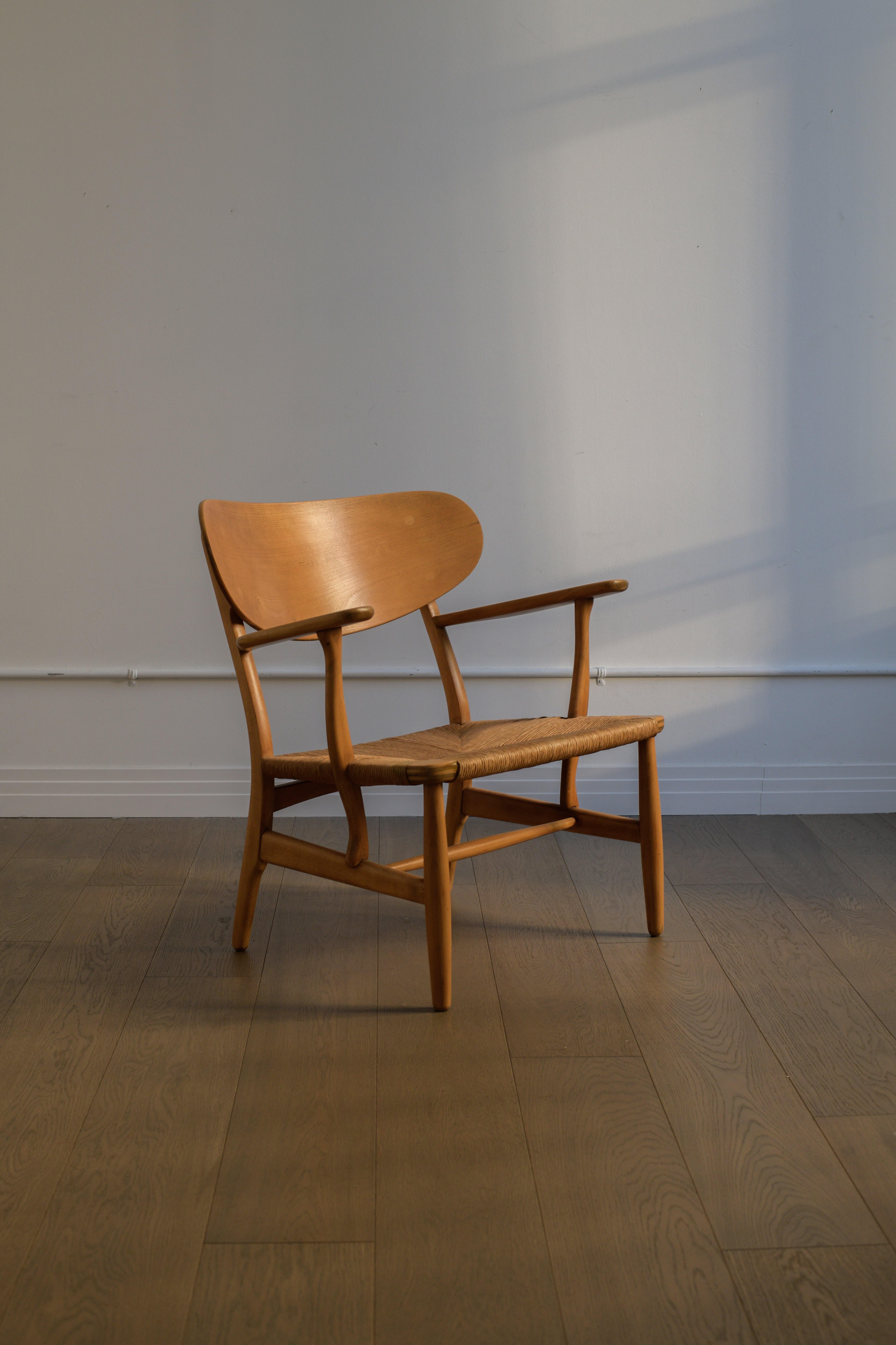 1951 HANS J. WEGNER Lounge Chair, model no. CH-22 manufactured by Carl Hansen & Søn, Denmark. Oak frame with rush seat. Underside of arm branded with designer.

In good vintage condition with a nice patina commensurate with its age. Was likely