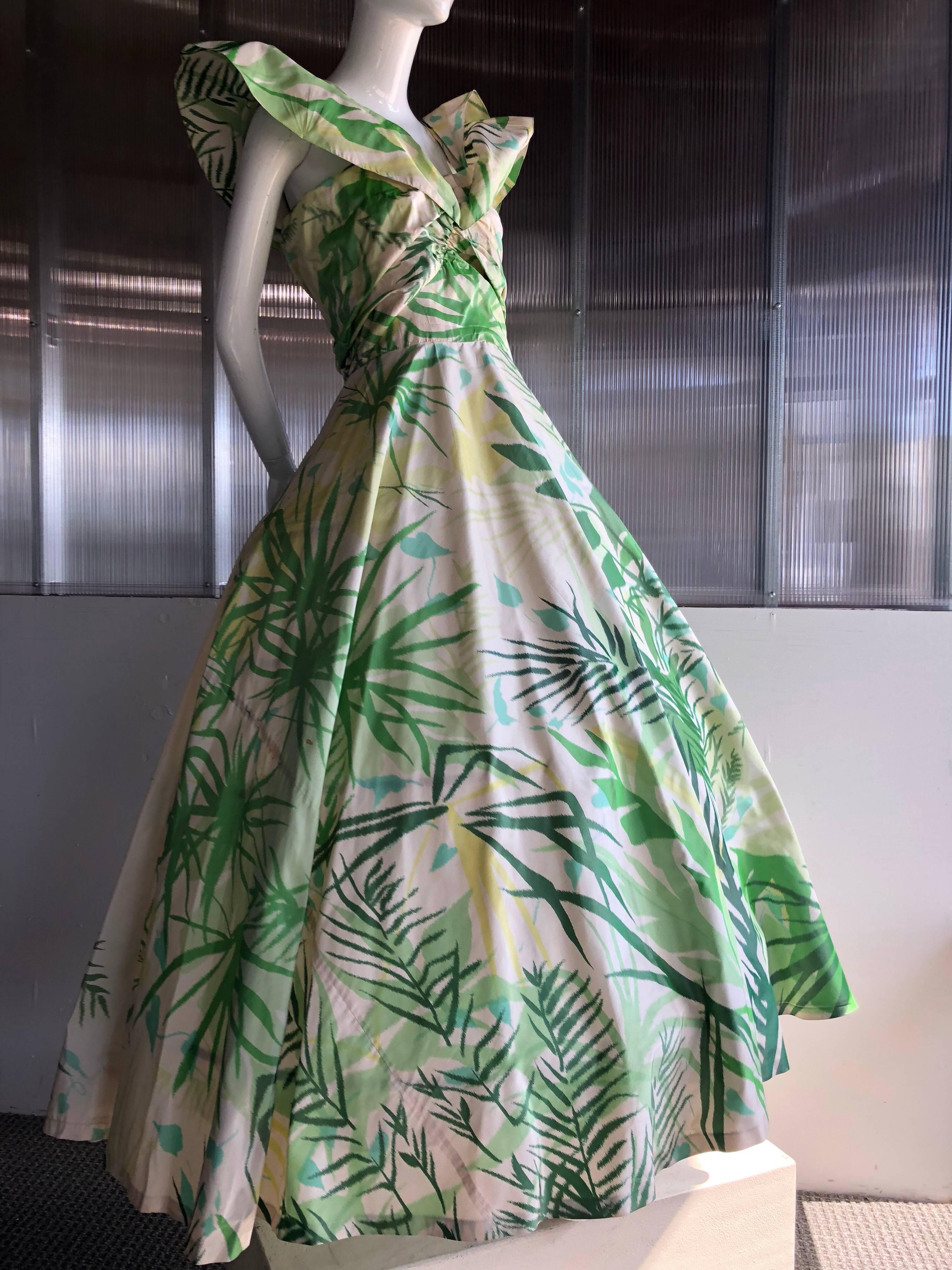 An incredible, rare 1952 Gilbert Adrian Original silk warp-printed taffeta gown in tropical leaf and palm frond motifs. Very, very full skirt, fitted, ruched bodice and spectacular wing-like shoulder ruffles. Bodice is boned. Back zipper.