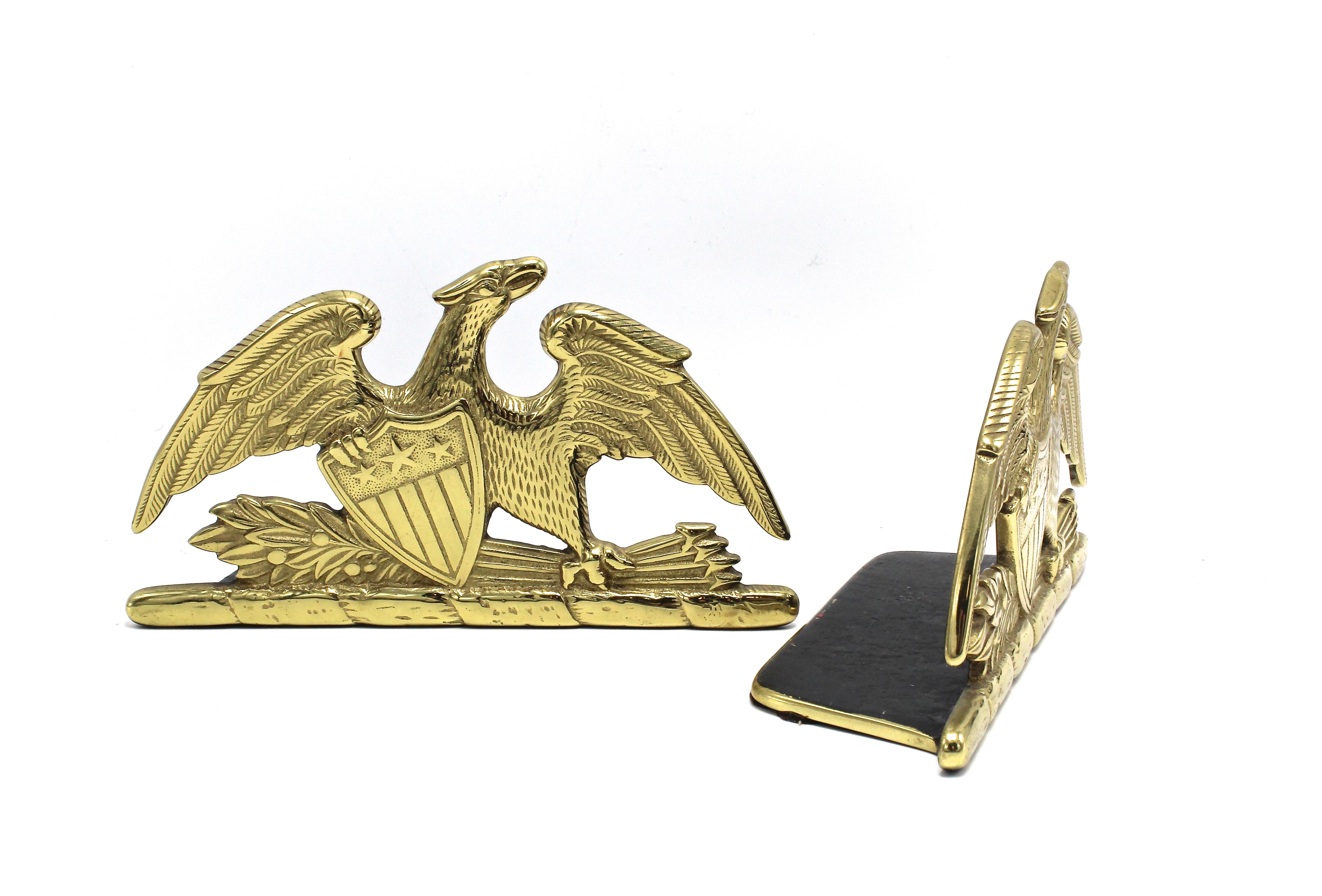 A beautiful pair of brass spread-wing eagle bookends by Virginia Metalcrafters, stamped 1952. The eagle is shown with its wings fully spread and a laurel branch and bundle of arrows clutched in its left talon. The eagle clutches a Union shield