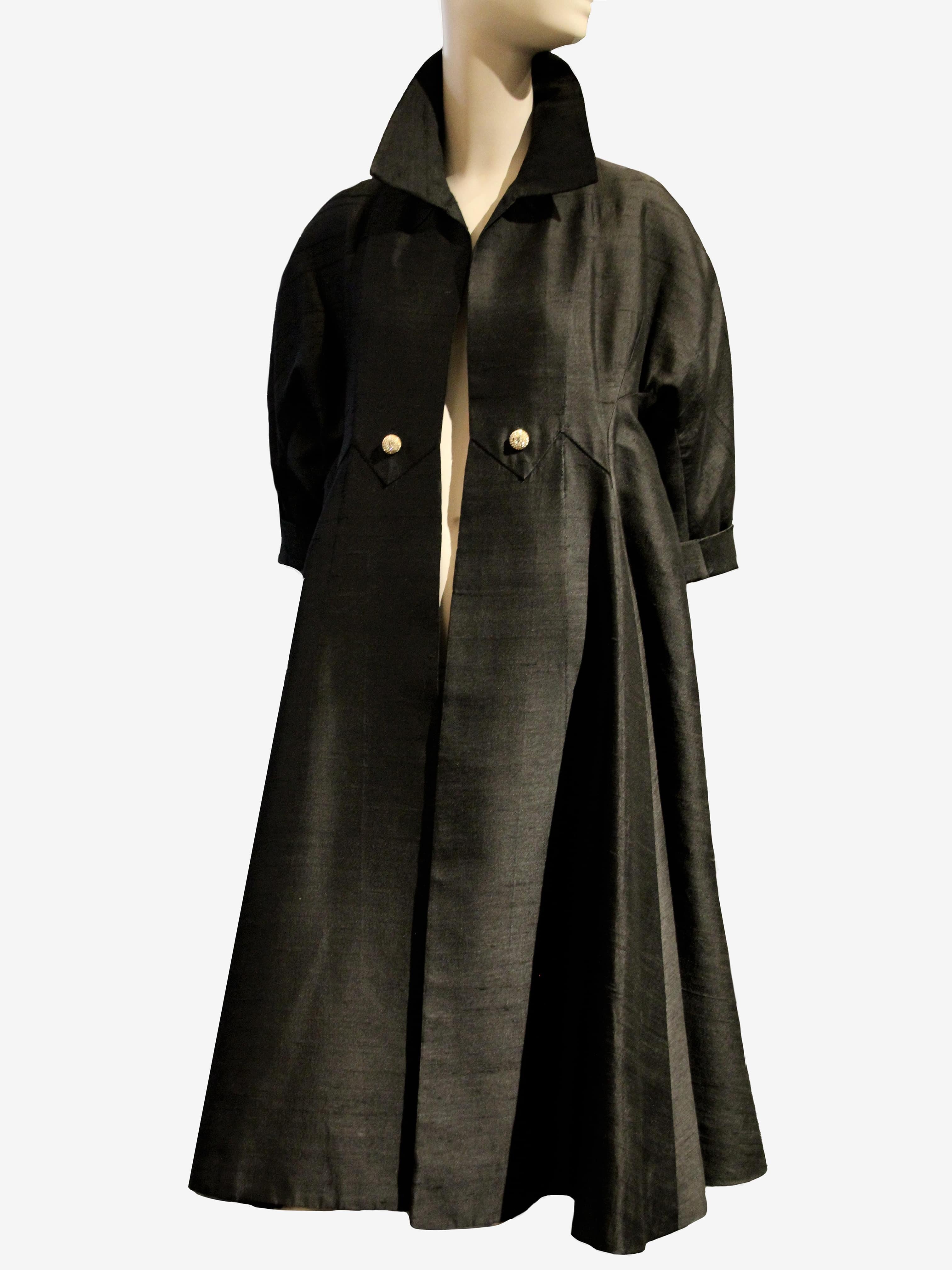 A gorgeous 1952 Christian Dior Spring/Summer Couture black dupioni silk opera coat: Cut in a full and dramatic swing style with volume falling from the raglan shoulders. The front panels are flatteringly lean. Two rhinestone buttons at front. No