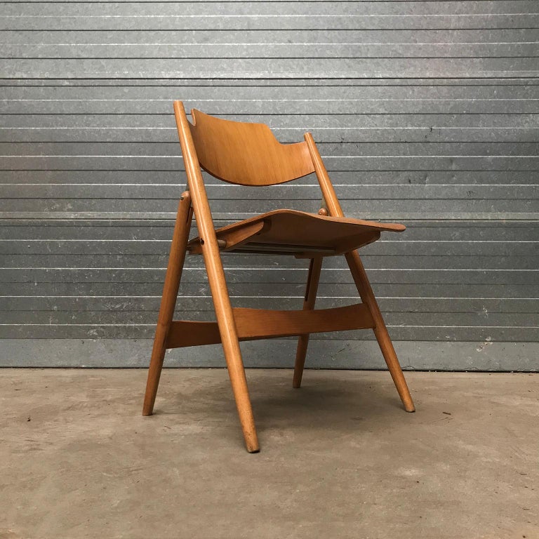 This wooden folding chair has a design with beautiful details and therefore it is interesting from any angle; the connections of the legs, the curved seat (pictures #8, #10, #16) and round details. The chair shows some traces of usage like some