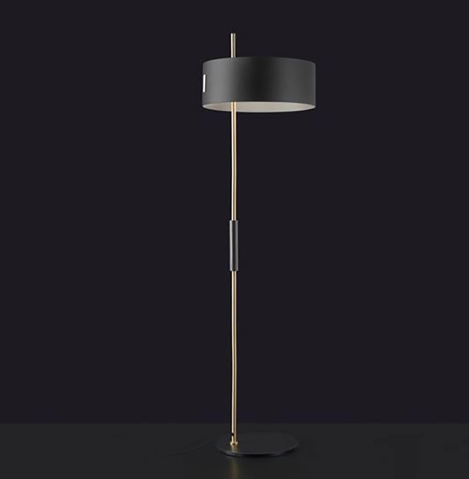 1953 floor lamp by Ostuni & Forti for Oluce. The lamp 1953 designed by Ostuni & Forti, elegantly recalls the style of those years, such as the use of a shade in the Classic cylindrical shape and the fine contrast of the satin gold stem and shade’s