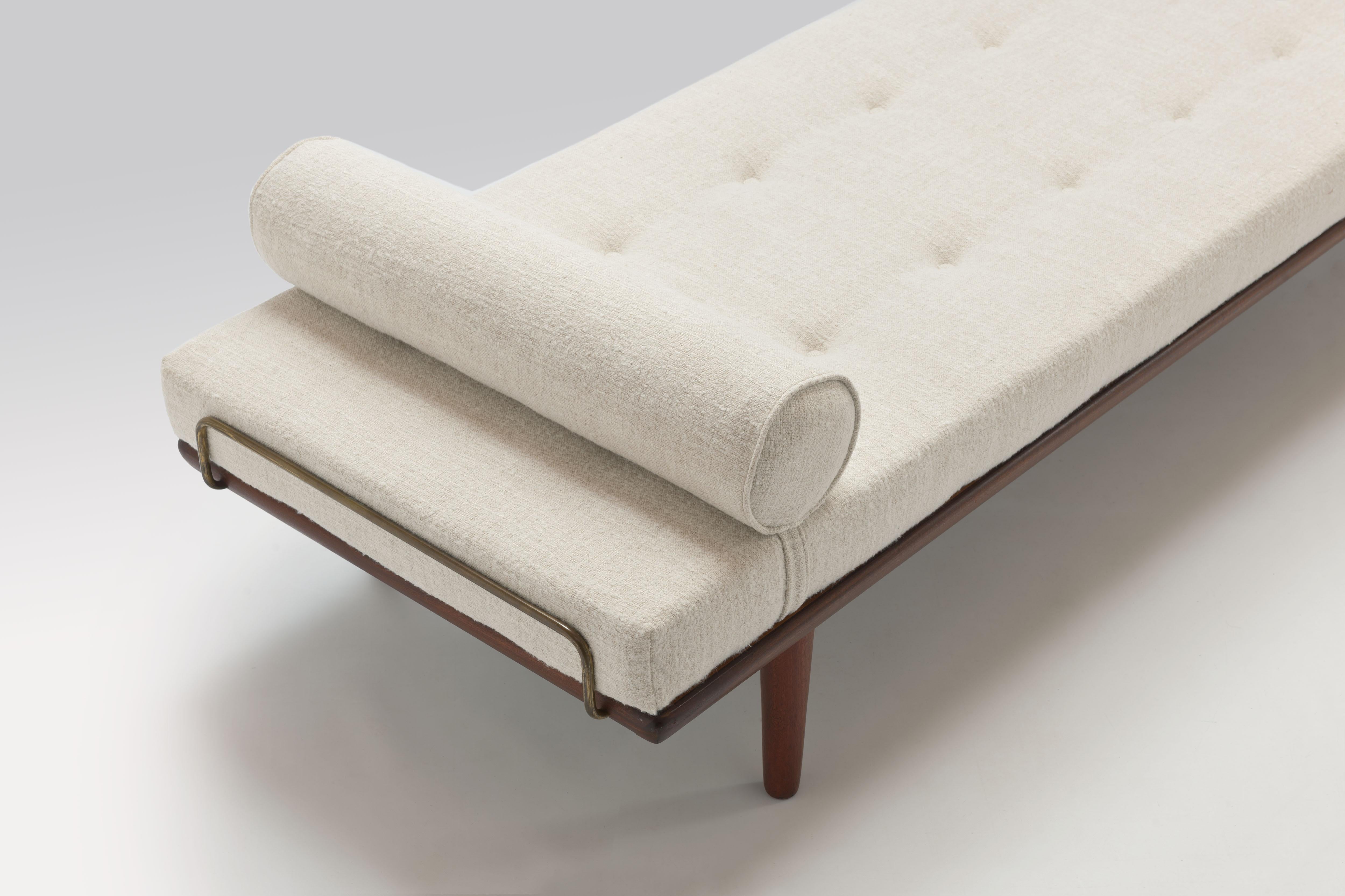 Daybed model GE19 from 1956 by Danish designer Hans J. Wegner constructed from solid teak with taper legs and beautiful brass mattress support bars on both sides. 
The daybed comes with a completely new mattress and neck roll pillow executed in a