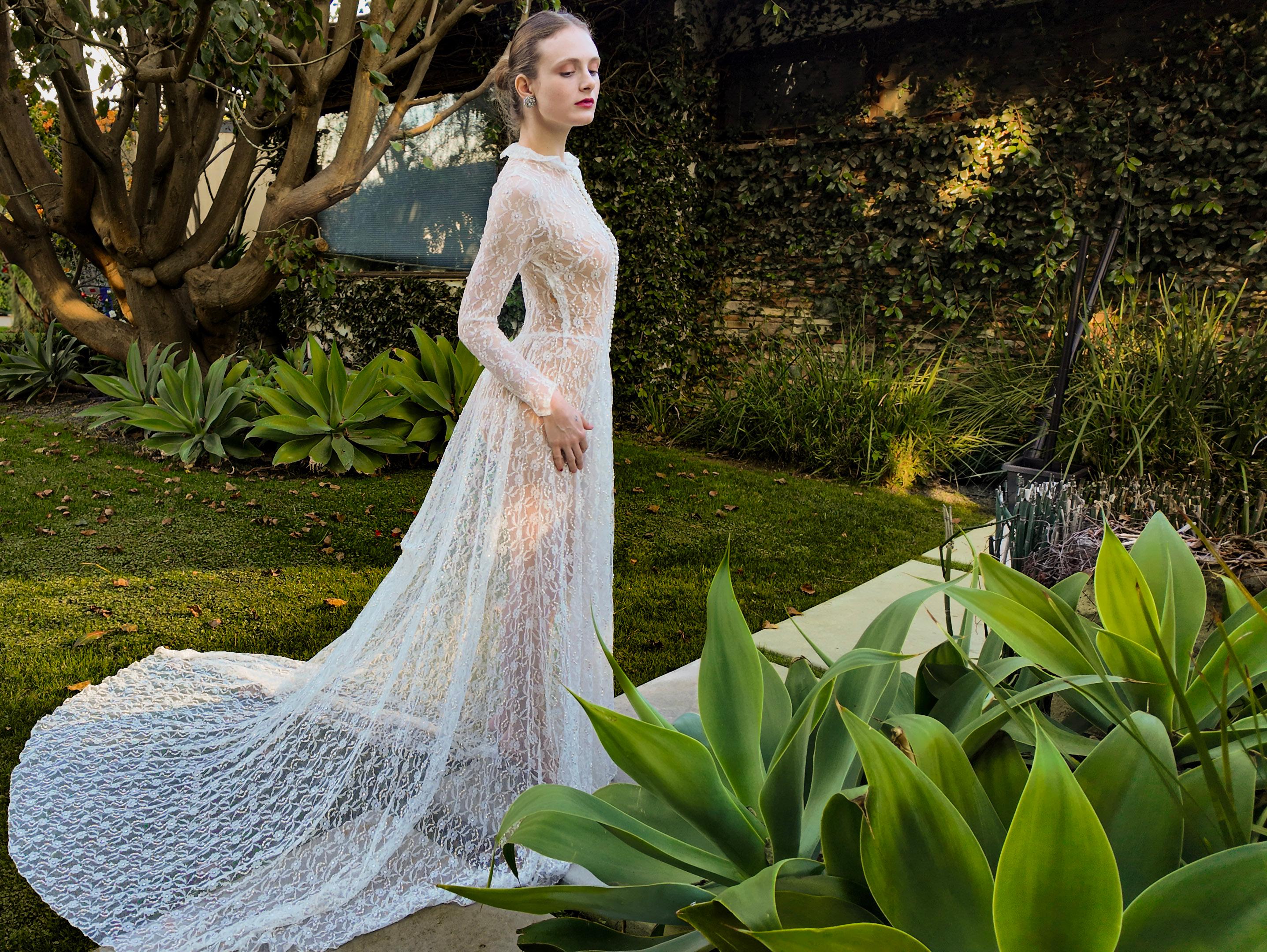 Embrace true vintage charm with our custom made 1958 Long Sleeve Button Front Collared Lace Wedding Gown with Train. Crafted with delicate sheer lace and a stunning train, this gown exudes elegance and sophistication. The collared neckline and