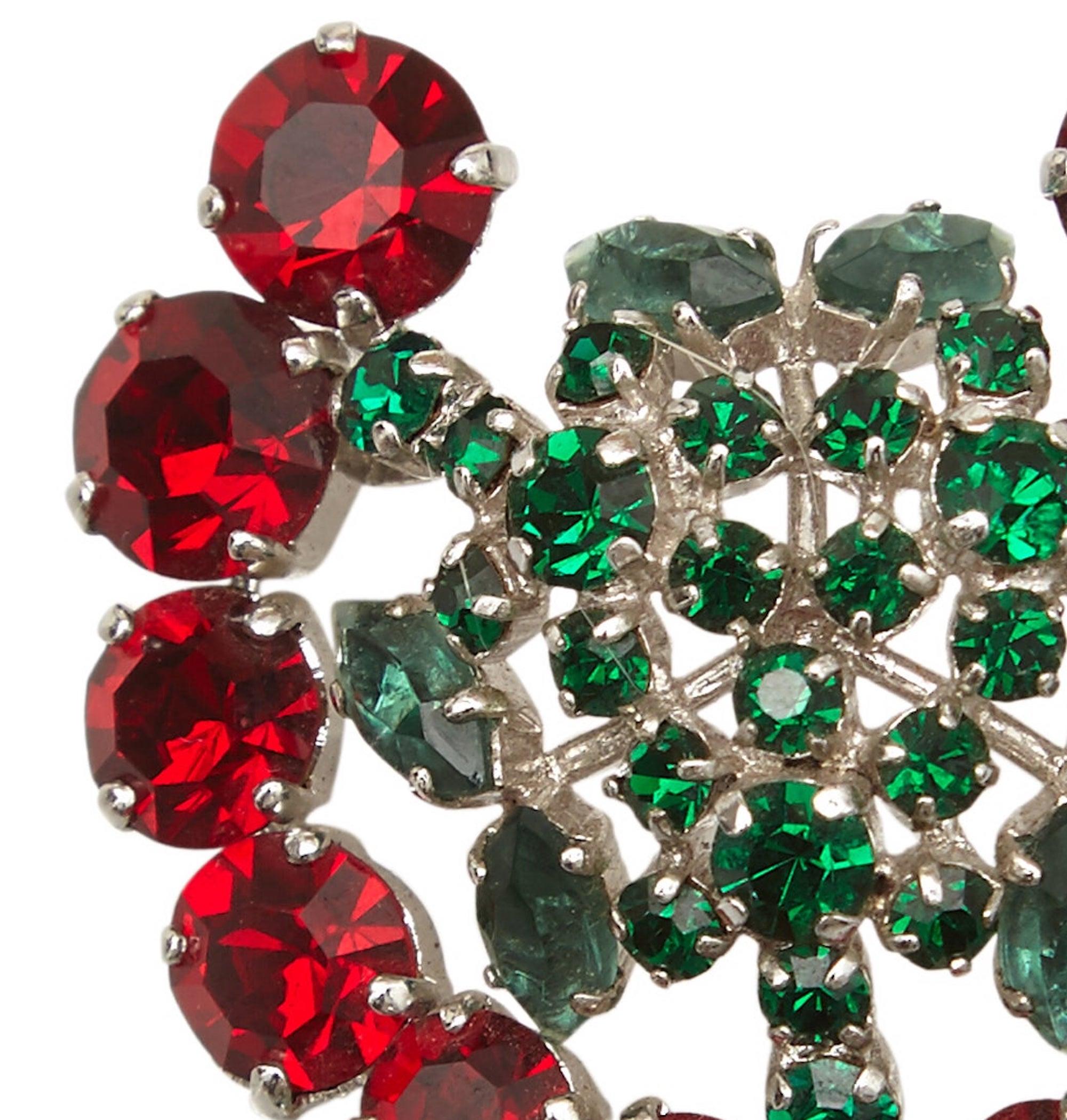 This desirable 1950s pin brooch with emerald green and ruby red prong set gemstones is Christian Dior by Henkel and Grosse and is in excellent vintage condition.  Rhodium plated, the green stones are prong set in two elaborate dome shaped