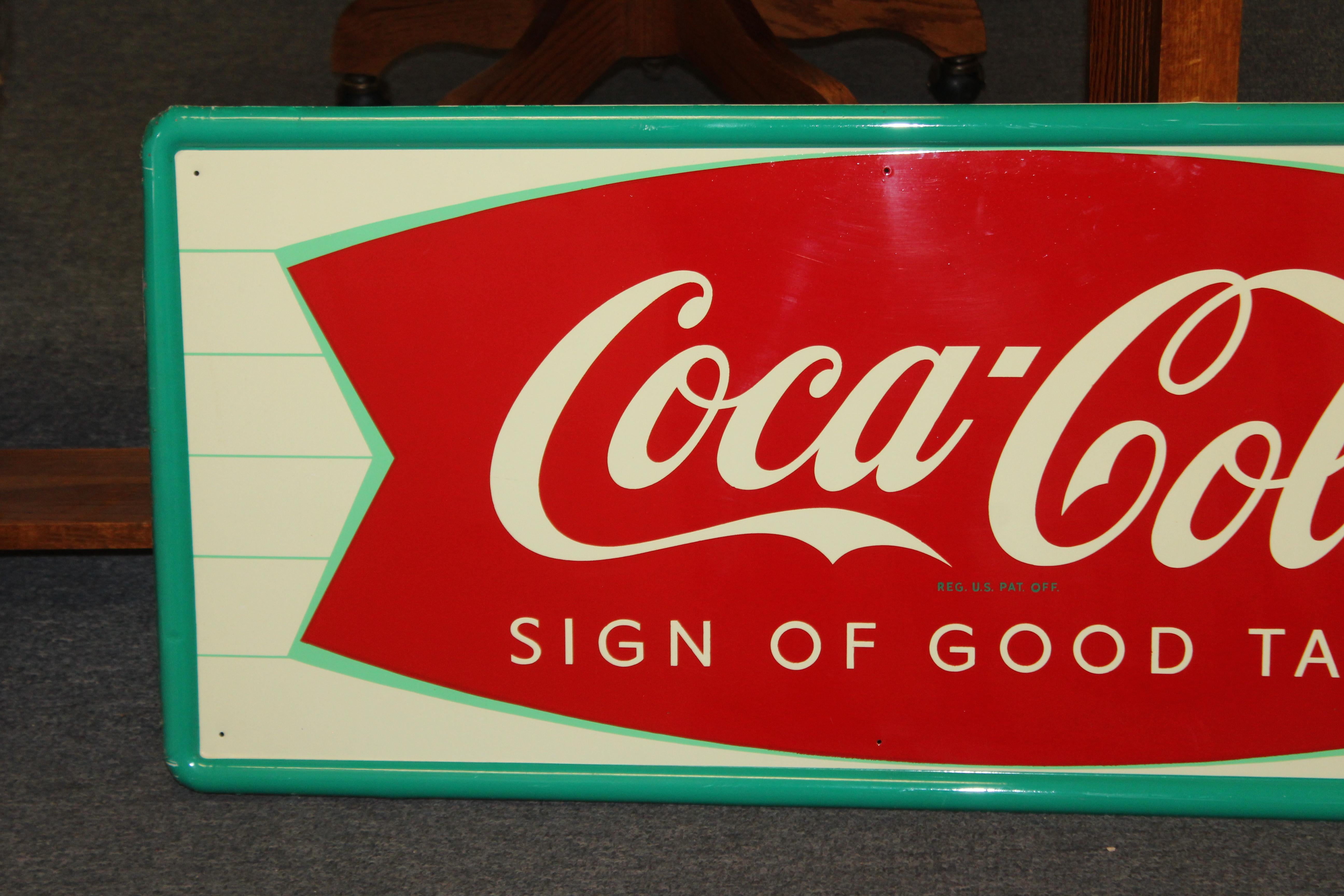 Cette enseigne semble être un nouveau vieux stock et annonce le logo classique en queue de poisson ainsi que la bouteille de Coca-Cola. Ce panneau est fabriqué par la Robertson Sign Company. Cette pièce de Coca-Cola fera partie de la collection de