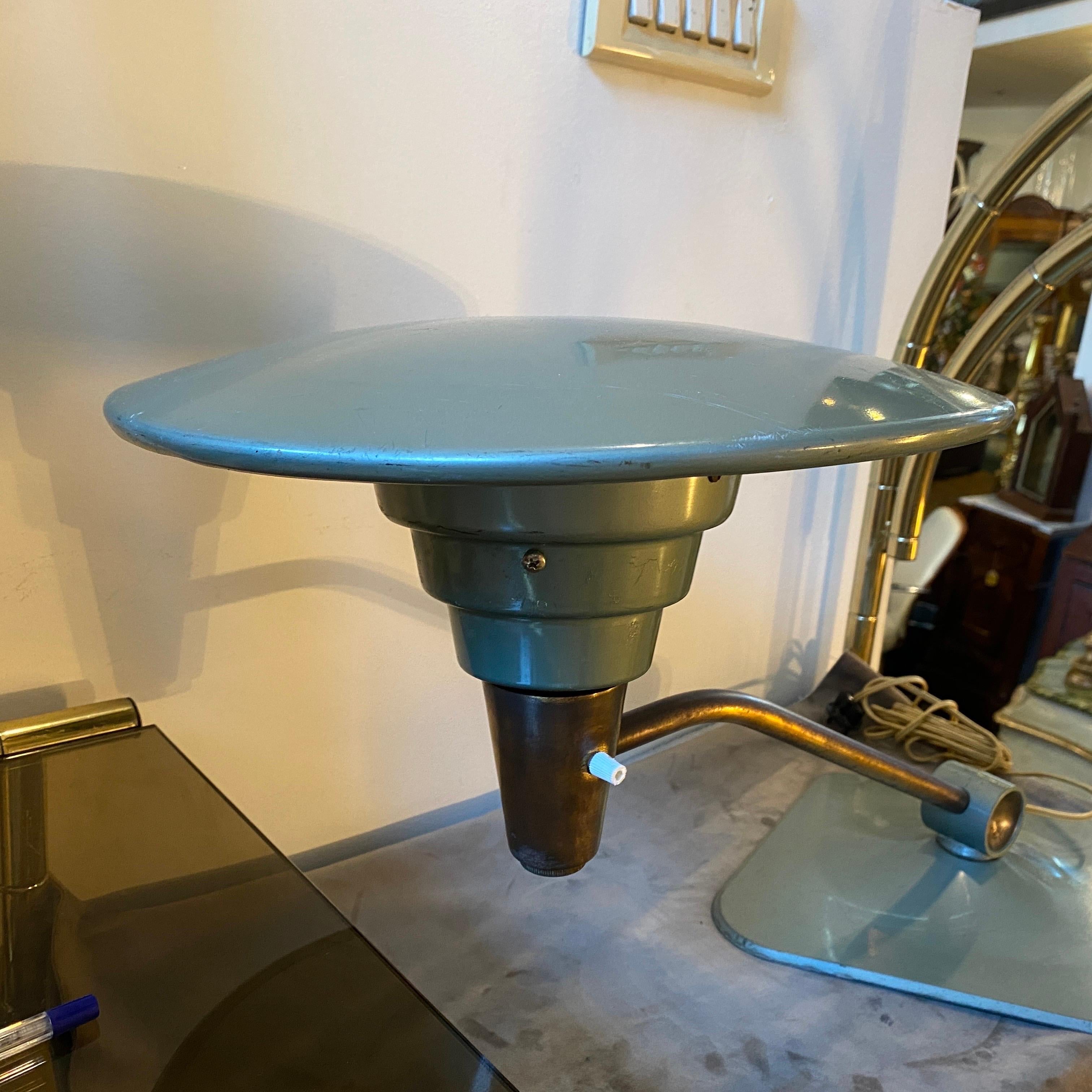 A table lamp, model 1056 designed and manufactured by Dazor in the United States of America, during the 1950's. It is made of brass and light blue painted aluminum. Original factory label visible on the underside of the shade.The stem can be rotated