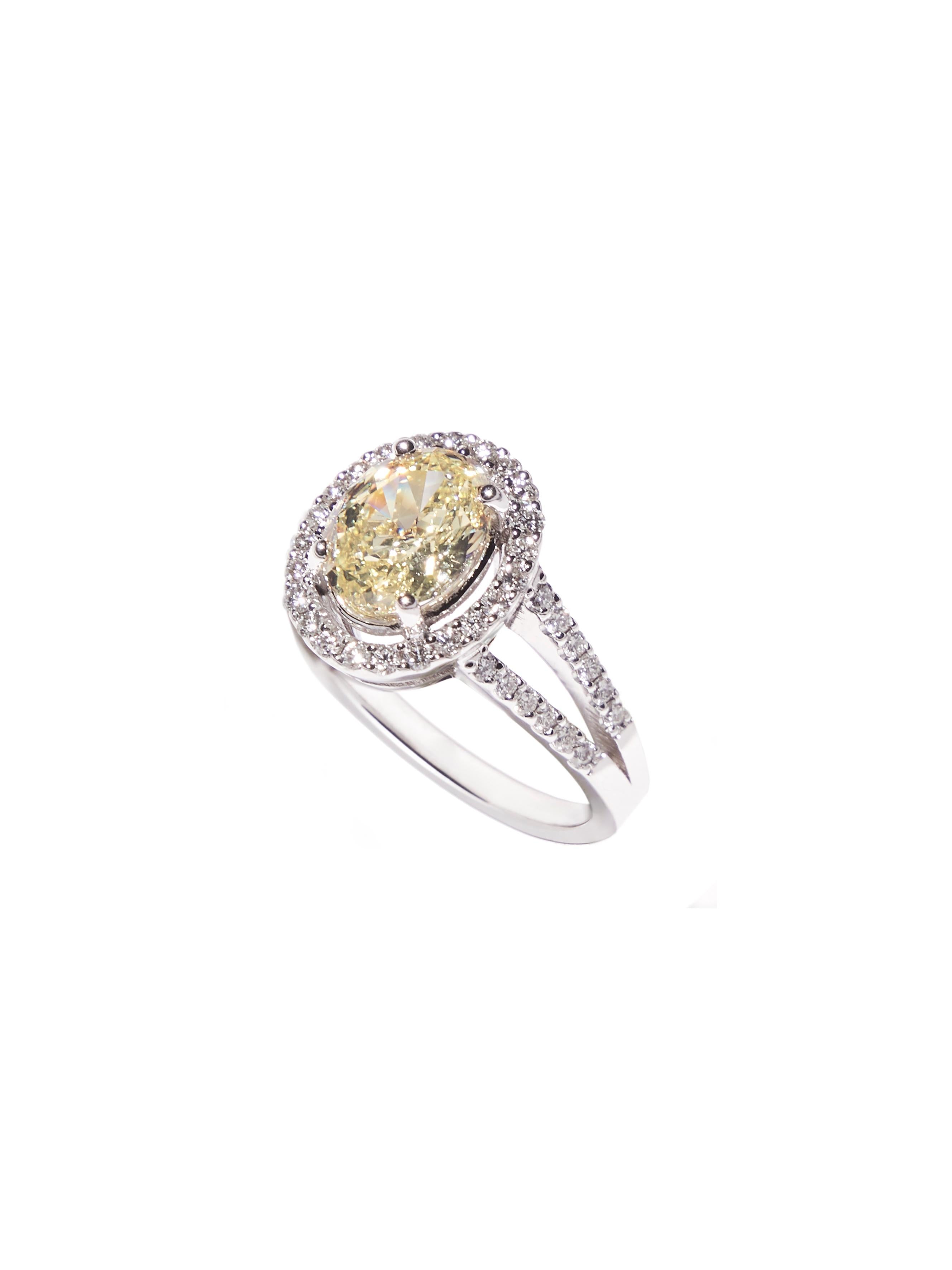 18 White gold split shank engagement ring featuring a natural fancy yellow oval center diamond totaling 1.96 carat and surrounded by 47 round white diamonds, a total of 0.50 ct in a TW/VS 

The GIA certified fancy yellow diamond has an even colour