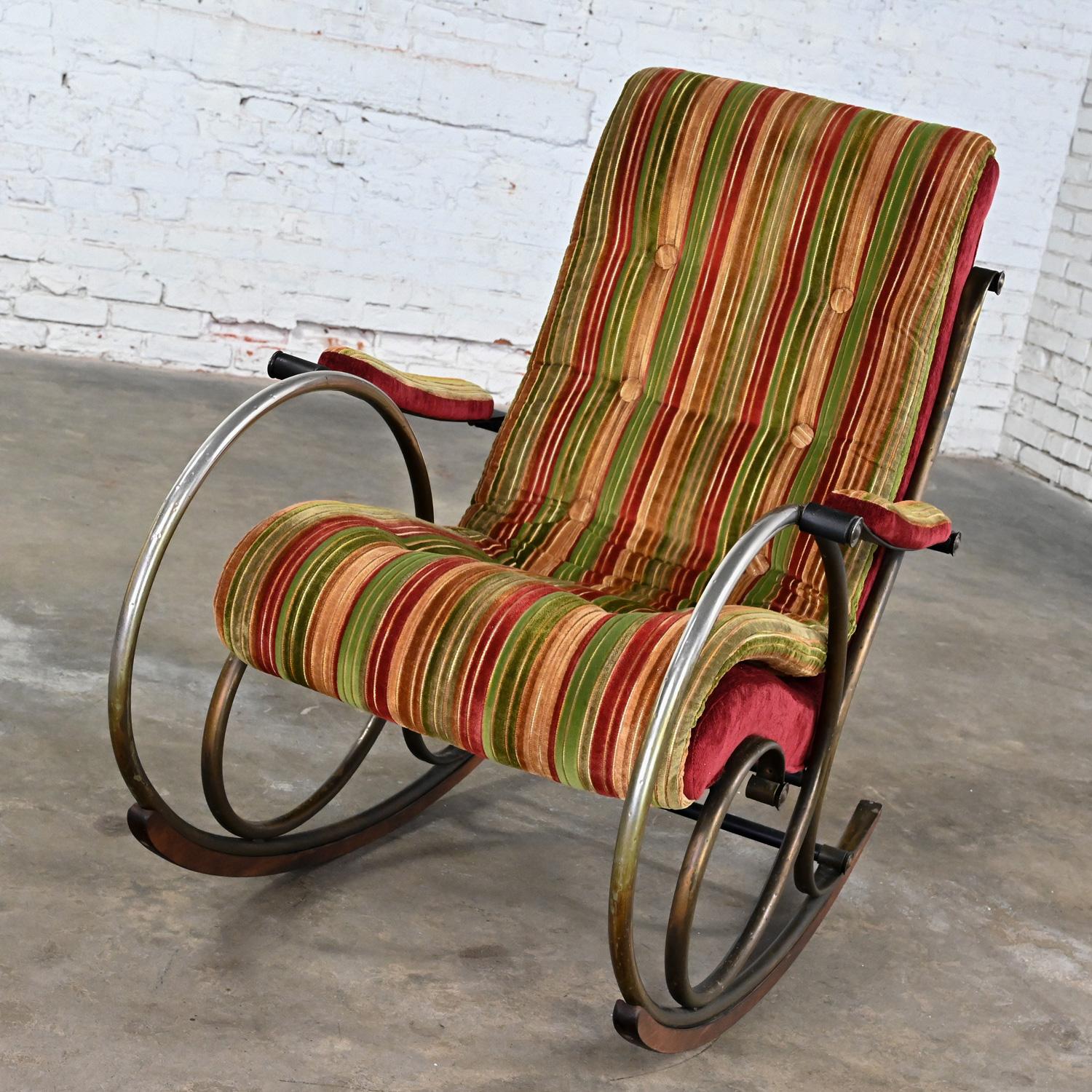 Marvelous vintage Neoclassic rocking chair by Lee Woodard comprised of a metal frame with an antiqued bronze finish and purposed hammered look & burgundy, gold, & green striped velvet chenille fabric with button detail, black accents, & wood tread
